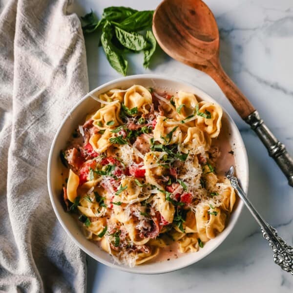 Creamy Tortellini with Prosciutto and Peas is made with cheese tortellini, crispy prosciutto, heavy cream, parmesan cheese, tomatoes, and peas. This Tortellini Ai Formaggio is such a popular tortellini pasta dish.