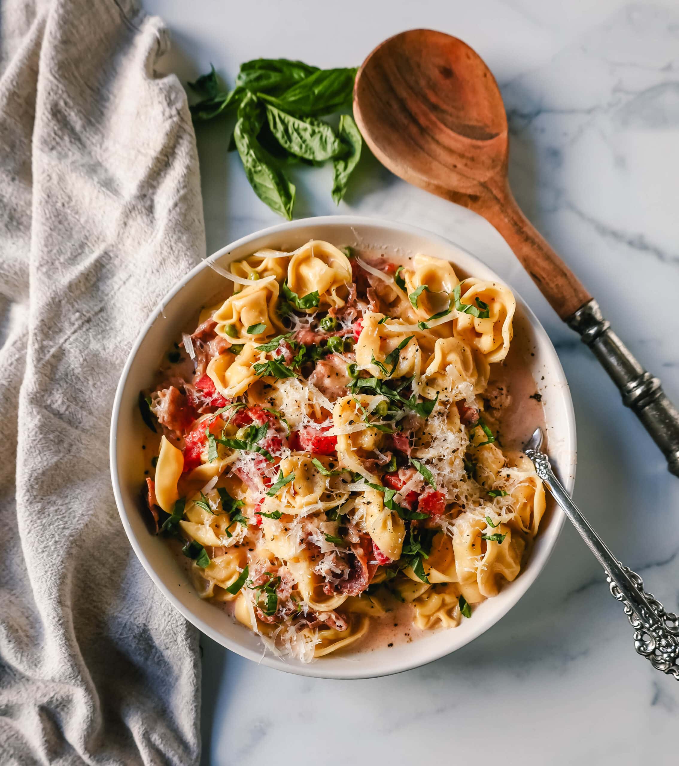 Creamy Tortellini with Prosciutto and Peas is made with cheese tortellini, crispy prosciutto, heavy cream, parmesan cheese, tomatoes, and peas. This Tortellini Ai Formaggio is such a popular tortellini pasta dish.
