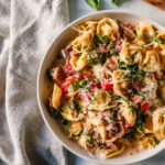 Creamy Tortellini with Prosciutto and Peas is made with cheese tortellini, crispy prosciutto, heavy cream, parmesan cheese, tomatoes, and peas. This Tortellini Ai Formaggio is such a popular tortellini pasta dish.
