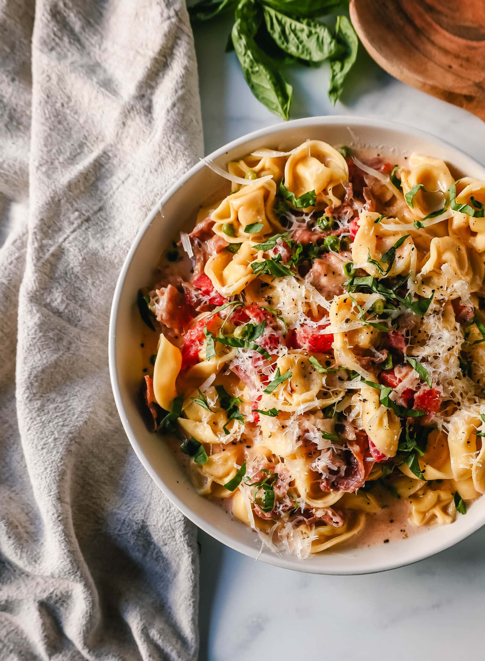 Creamy Tortellini with Prosciutto and Peas is made with cheese tortellini, crispy prosciutto, heavy cream, parmesan cheese, tomatoes, and peas. This Tortellini Ai Formaggio is such a popular tortellini pasta dish.