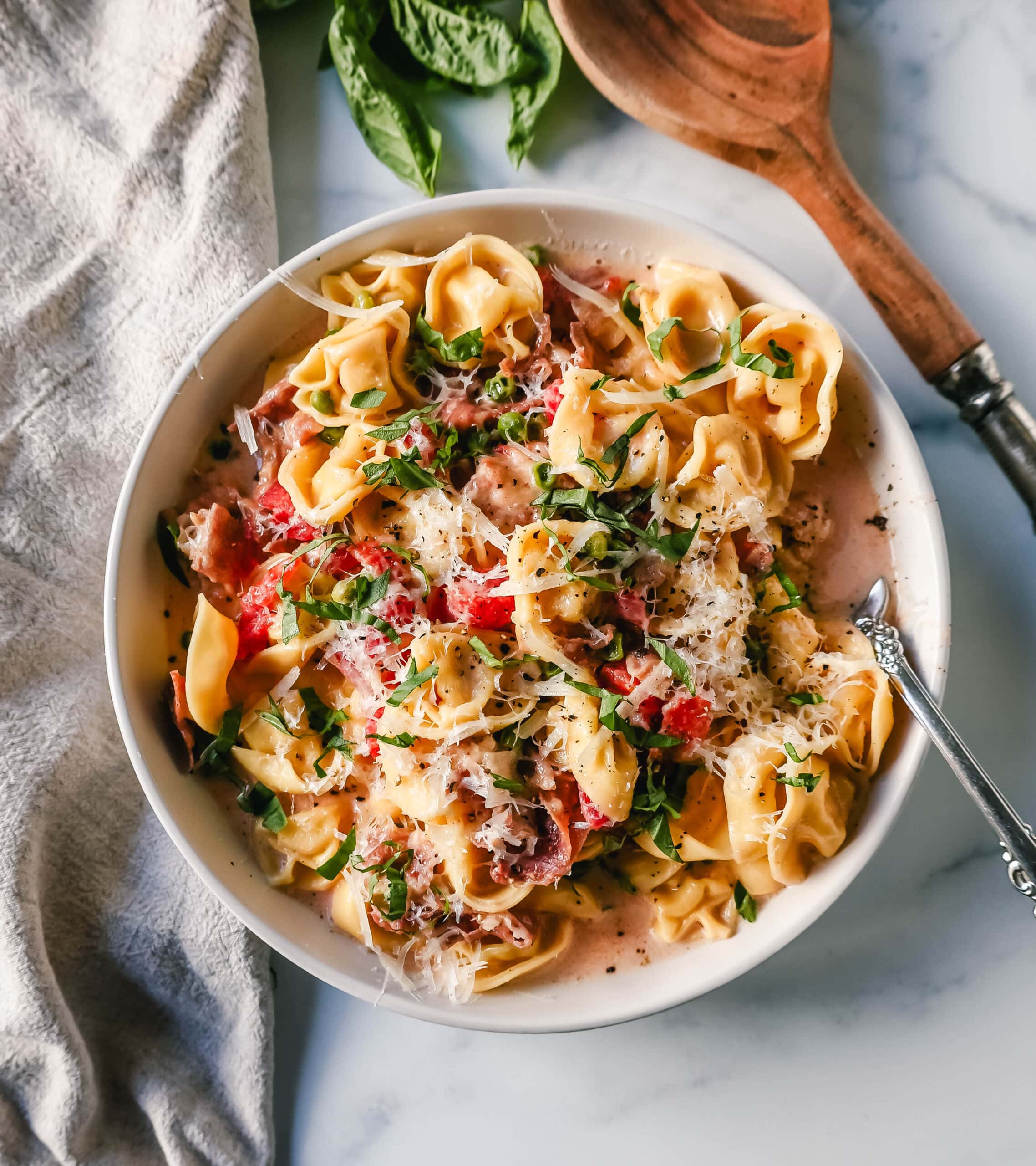 Creamy Tortellini with Prosciutto and Peas is made with cheese tortellini, crispy prosciutto, heavy cream, parmesan cheese, tomatoes, and peas. This Tortellini Ai Formaggio is such a popular tortellini pasta dish.