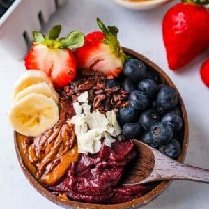 Acai Smoothie Bowl is made with a Brazilian berry mixed with frozen fruits and topped with fresh fruit and granola. How to make the popular acai smoothie bowls at home.