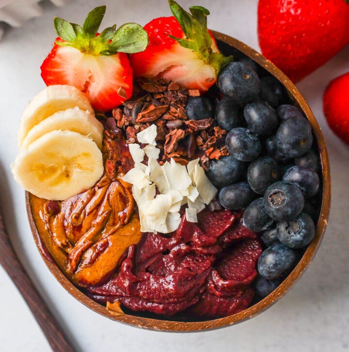 Acai Smoothie Bowl is made with a Brazilian berry mixed with frozen fruits and topped with fresh fruit and granola. How to make the popular acai smoothie bowls at home.