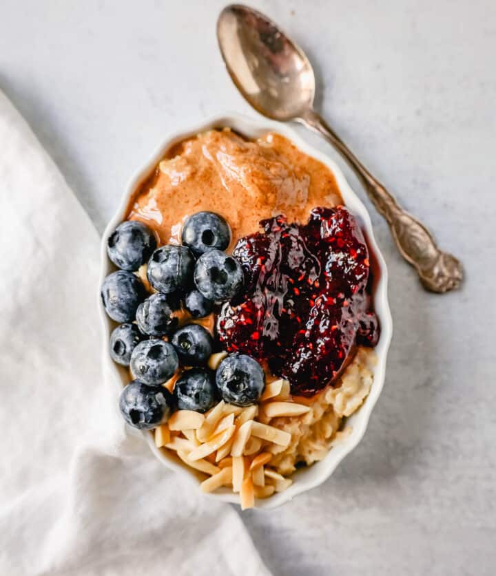 Oatmeal with Almond Butter, Jam, and Almonds. How to make creamy oatmeal with your favorite toppings combinations. I am sharing a list of all of the popular oatmeal toppings ideas to serve on a cold winter day and how to make the best bowl of oatmeal!