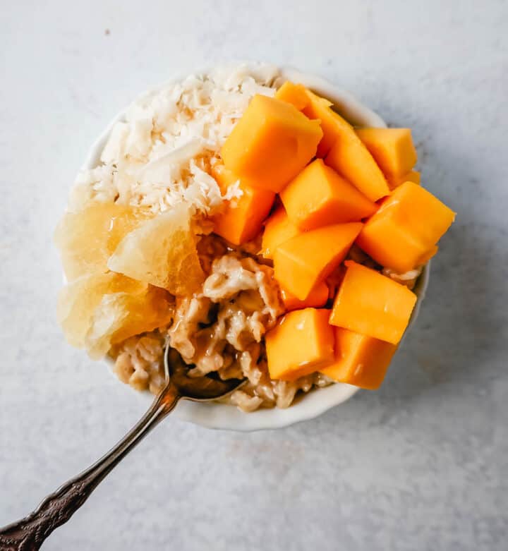 Tropical Oatmeal with Mango and Coconut Flakes. How to make creamy oatmeal with your favorite toppings combinations. I am sharing a list of all of the popular oatmeal toppings ideas to serve on a cold winter day and how to make the best bowl of oatmeal!