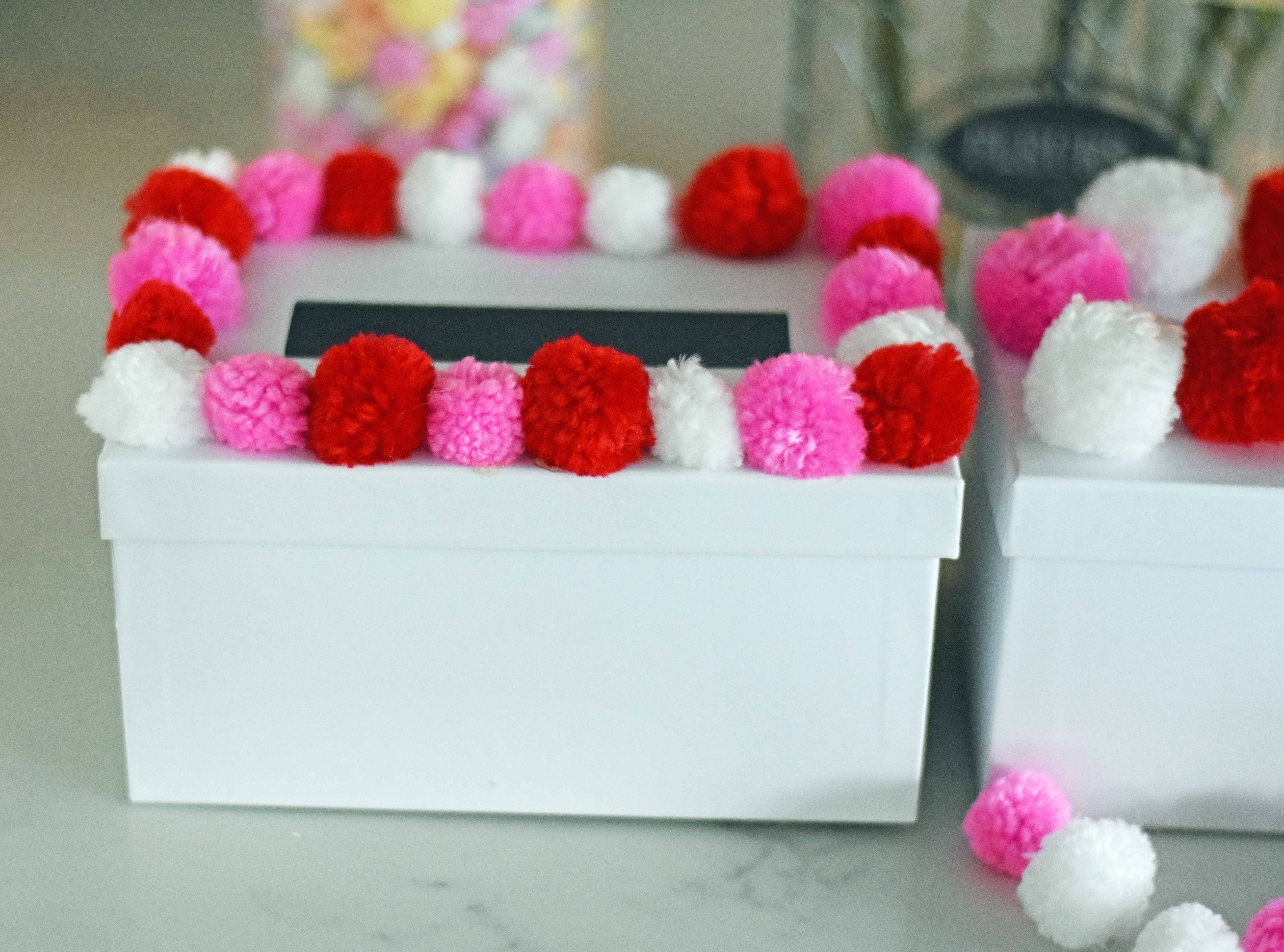 How to decorate Valentine's Day boxes with pom poms. Pom Poms Valentine's Day boxes.  Easy Valentine's Day boxes for school. Valentine's Day decorating ideas. www.modernhoney.com