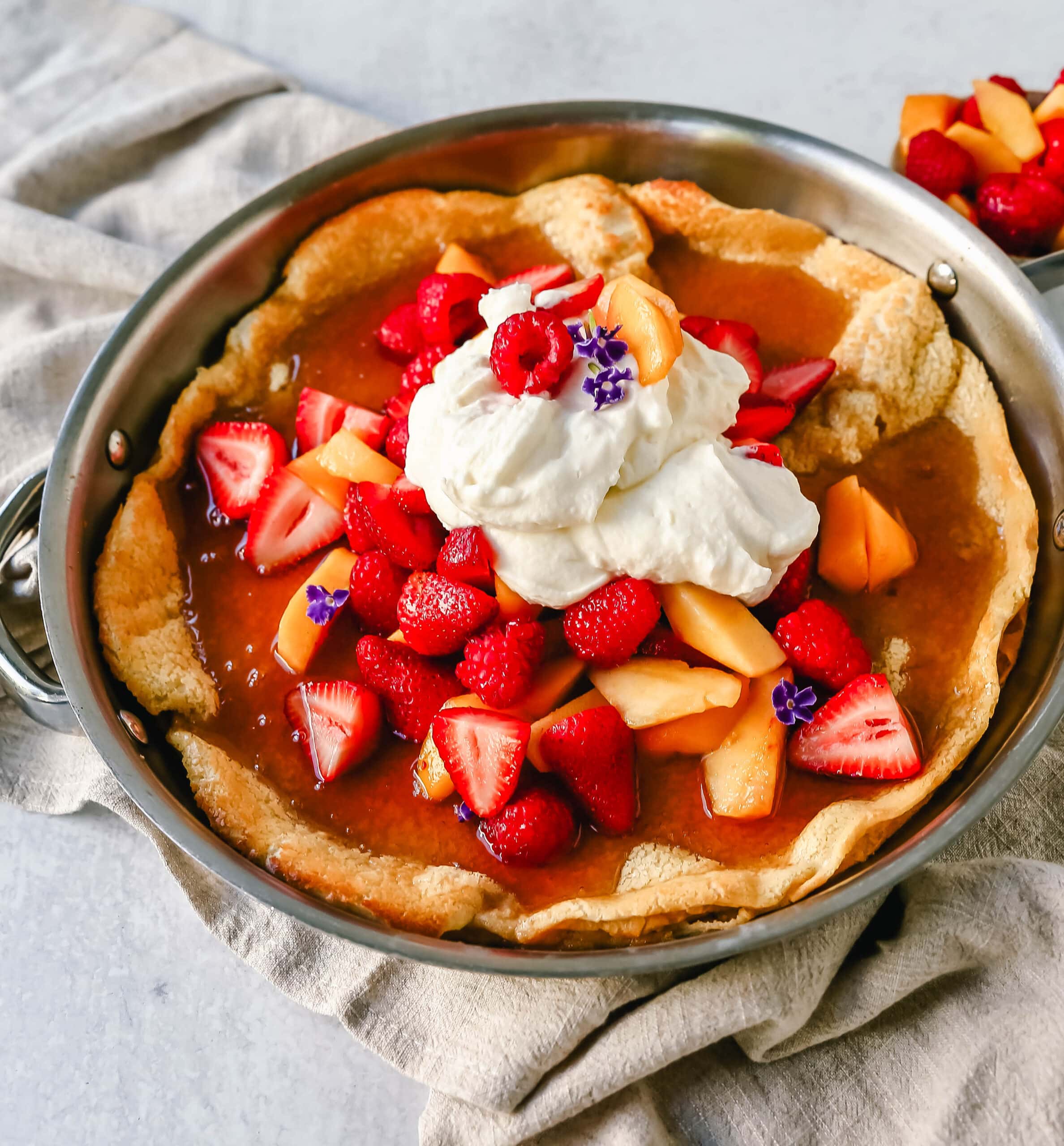 A decadent Dutch Baby Puff Pancake is made with milk, eggs, sugar, flour, and vanilla, and baked in a cast iron skillet in the oven until it puffs up and becomes a golden brown. A delicious and easy breakfast dish!