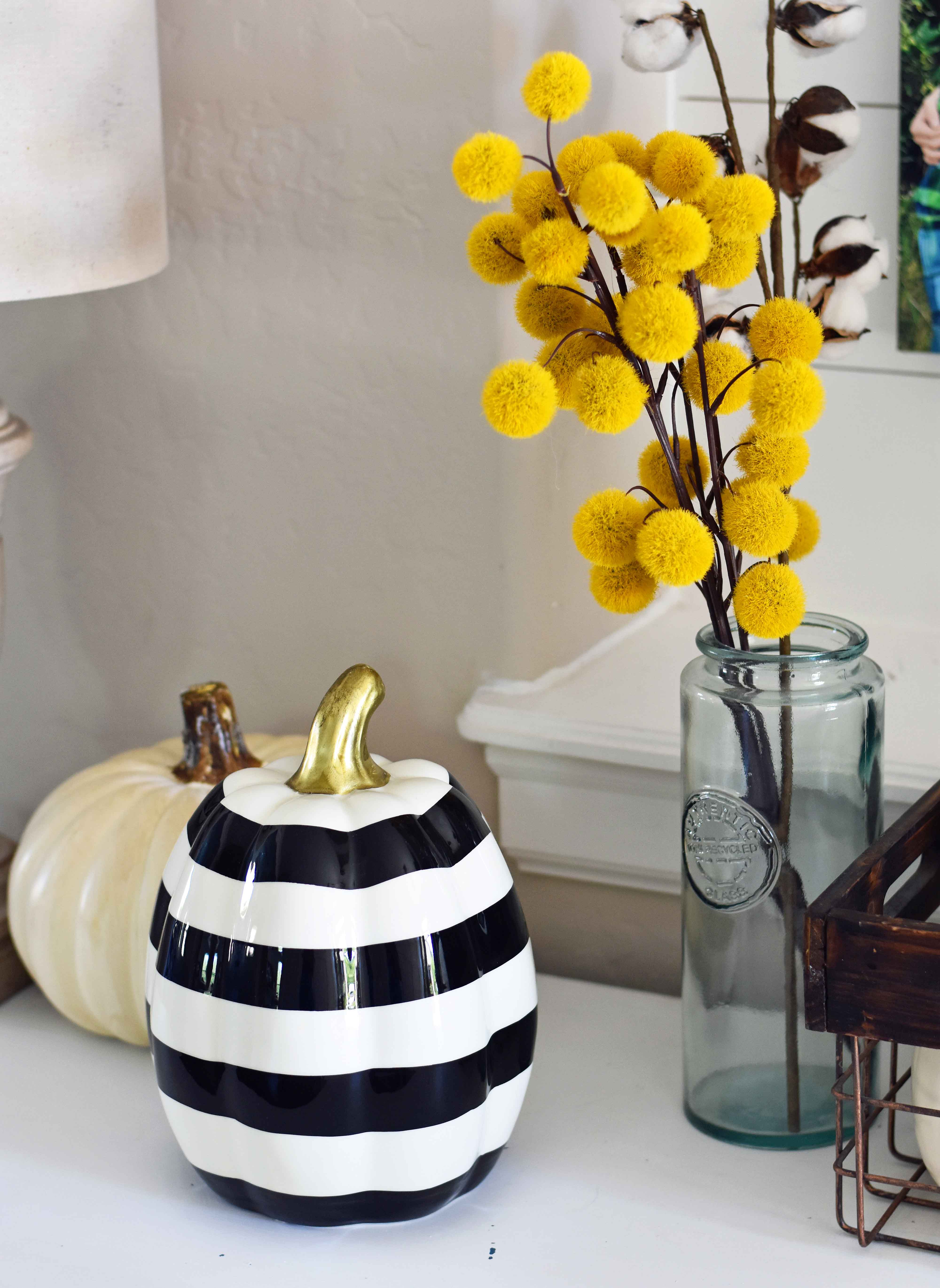 Fall Entry Decor Ideas. Craspedia Yellow Billy Ball Flowers in vintage vases. White pumpkins in wire baskets. Black and white striped pumpkin. Natural lamps, white entry table, and fall decor. Fixer Upper cotton ball stems. How to decorate your home for Fall.