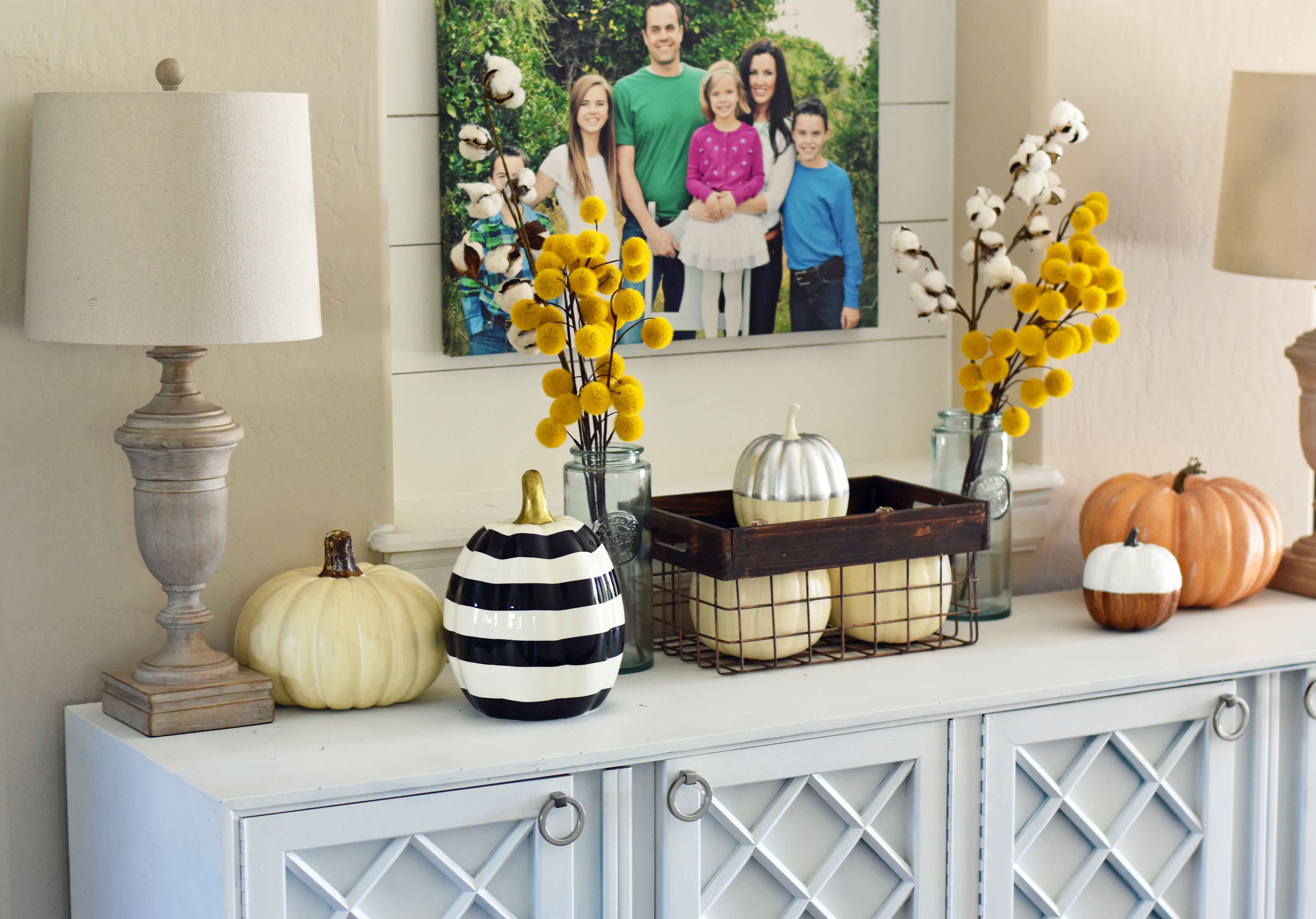 Fall Entry Decor Ideas. Craspedia Yellow Billy Ball Flowers in vintage vases. White pumpkins in wire baskets. Black and white striped pumpkin. Natural lamps, white entry table, and fall decor. Fixer Upper cotton ball stems. How to decorate your home for Fall.