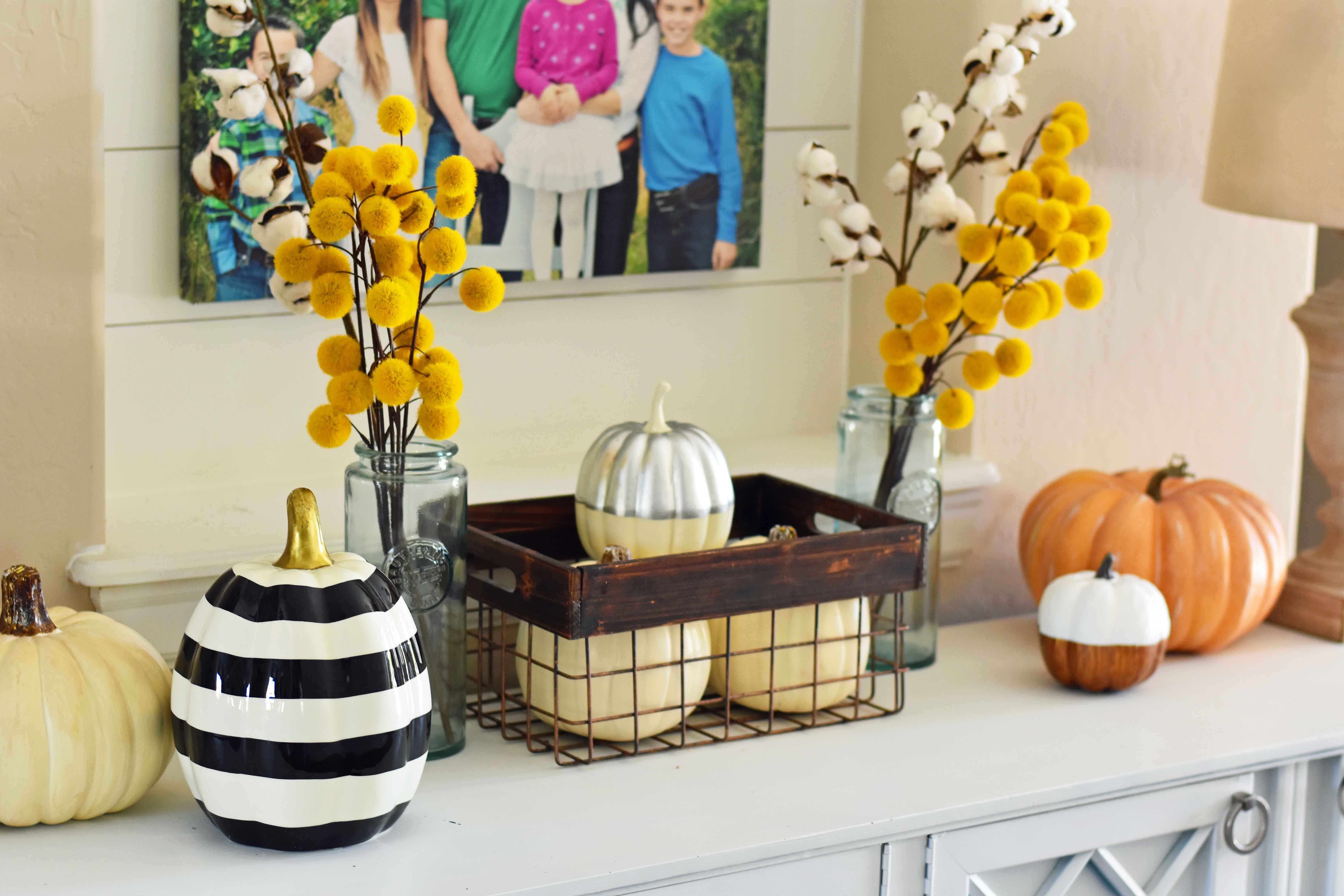 Fall Entry Decor Ideas. Craspedia Yellow Billy Ball Flowers in vintage vases. White pumpkins in wire baskets. Black and white striped pumpkin. Natural lamps, white entry table, and fall decor. Fixer Upper cotton ball stems. How to decorate your home for Fall.