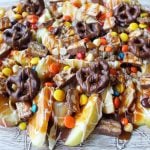 Candy Madness Caramel Apple Nachos by Modern Honey. Crisp Apples topped with Salted Caramel, White Chocolate, M &M's, Reeses Pieces, Heath Toffee Bits, Snickers, and Chocolate Covered Pretzels. These Caramel Apple Nachos are much easier than making caramel apples and will be a huge hit at your next party!