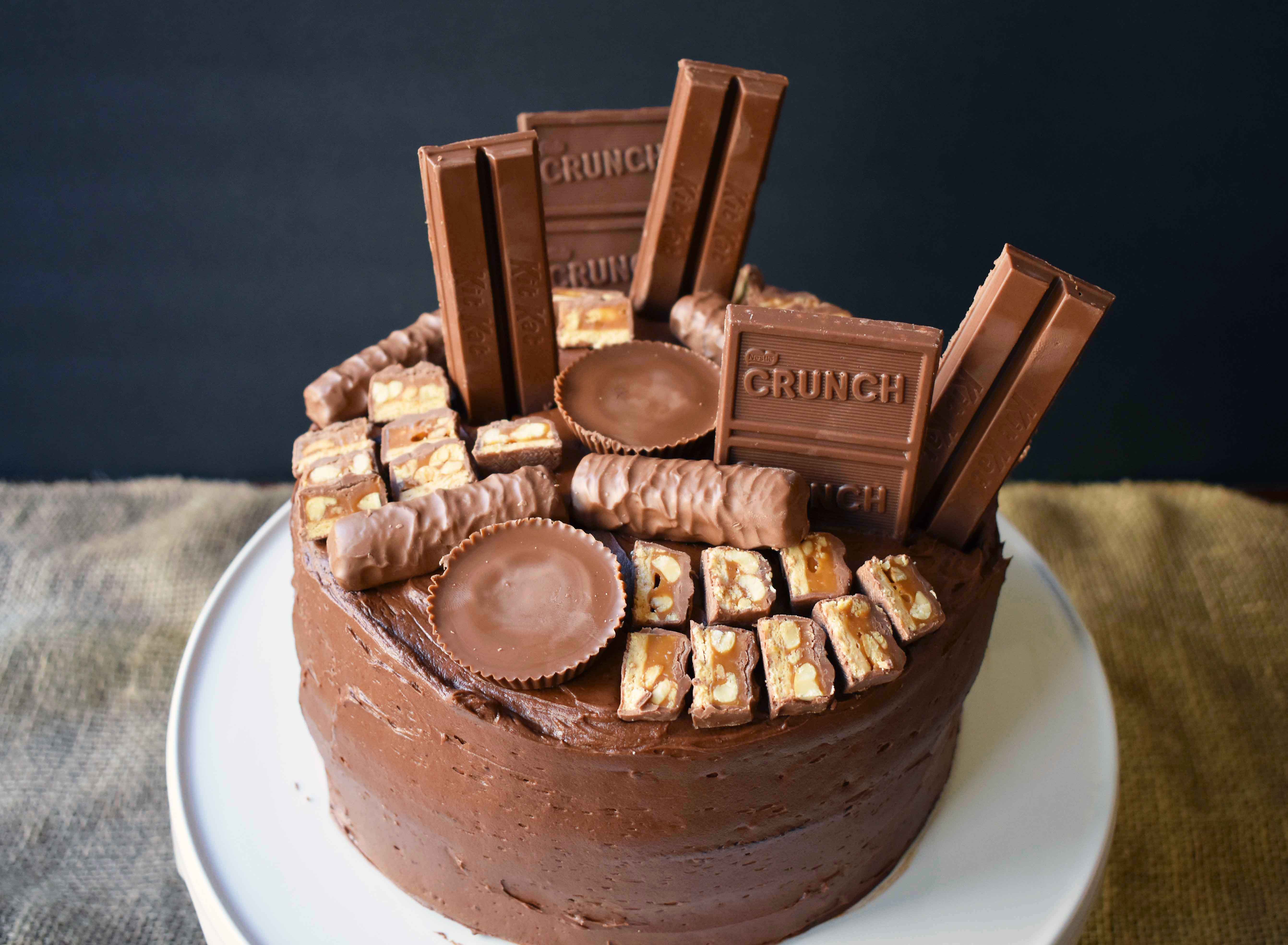 Candy Bar Stash Chocolate Cake by Modern Honey. Perfect chocolate cake topped with chocolate buttercream and the most popular candy bars. It's the ultimate Chocolate Candy Bar Cake.