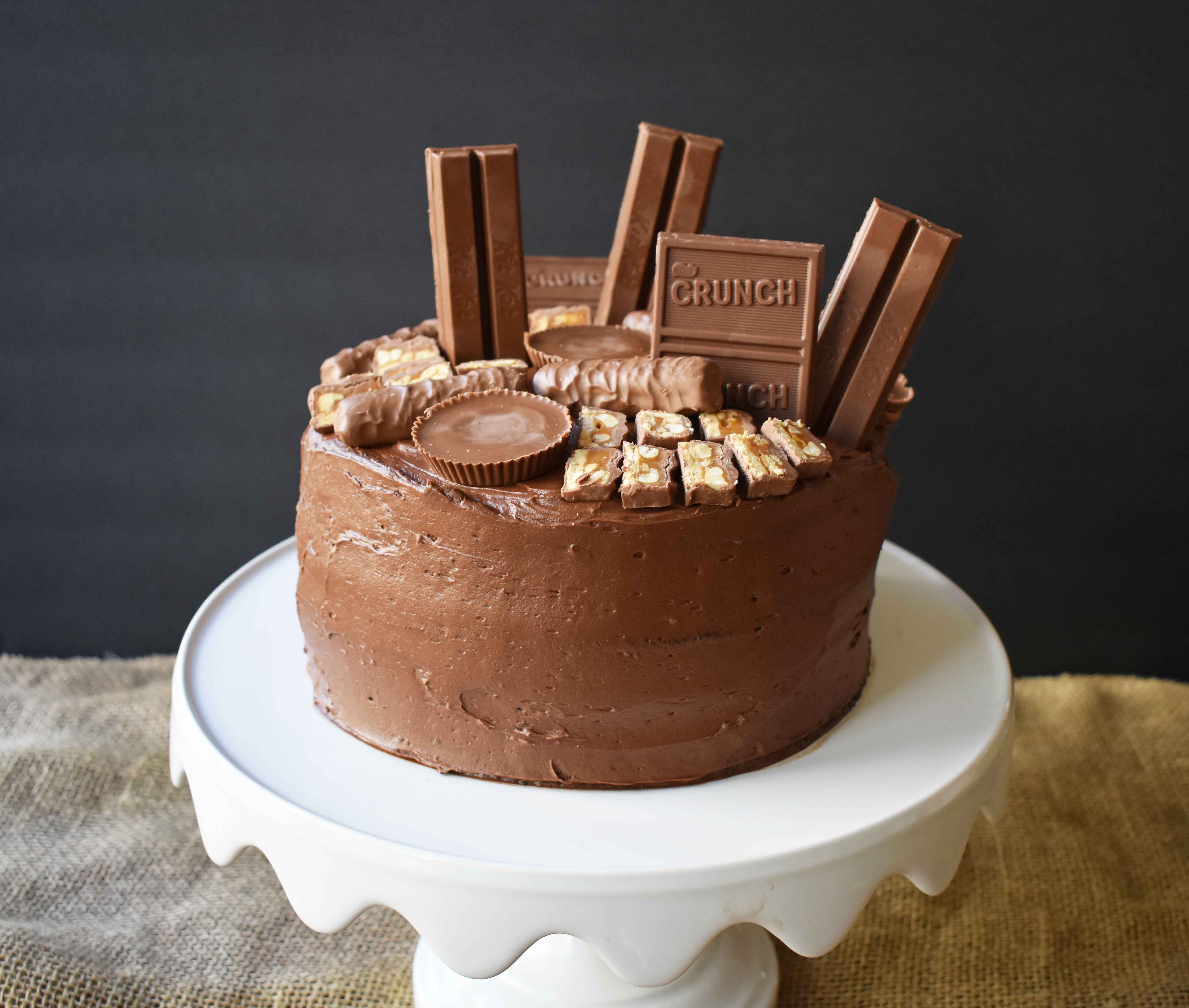 Candy Bar Stash Chocolate Cake by Modern Honey. Perfect chocolate cake topped with chocolate buttercream and the most popular candy bars. It's the ultimate Chocolate Candy Bar Cake.