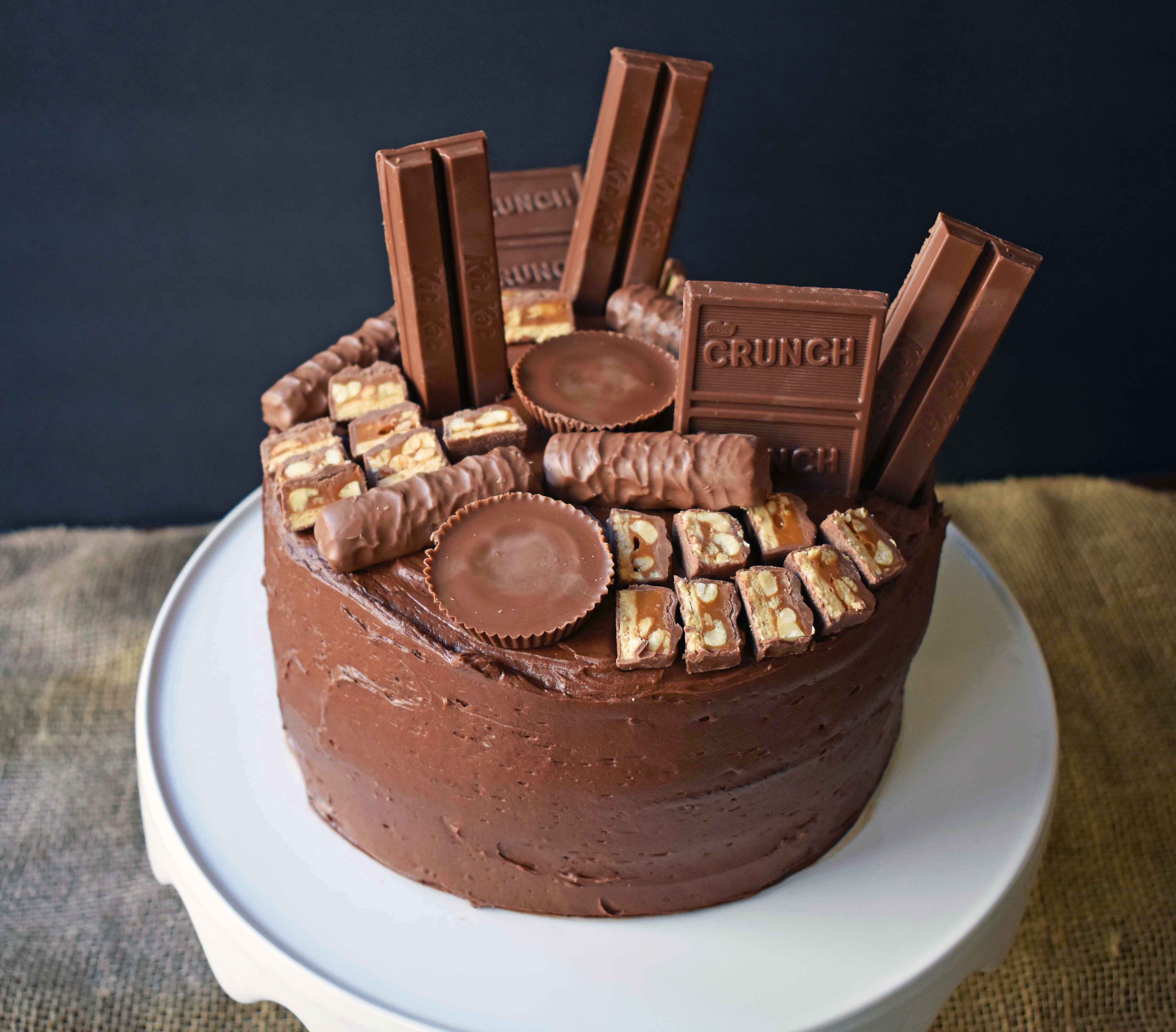 Candy Bar Stash Chocolate Cake by Modern Honey. Perfect chocolate cake topped with chocolate buttercream and the most popular candy bars. It's the ultimate Chocolate Candy Bar Cake.