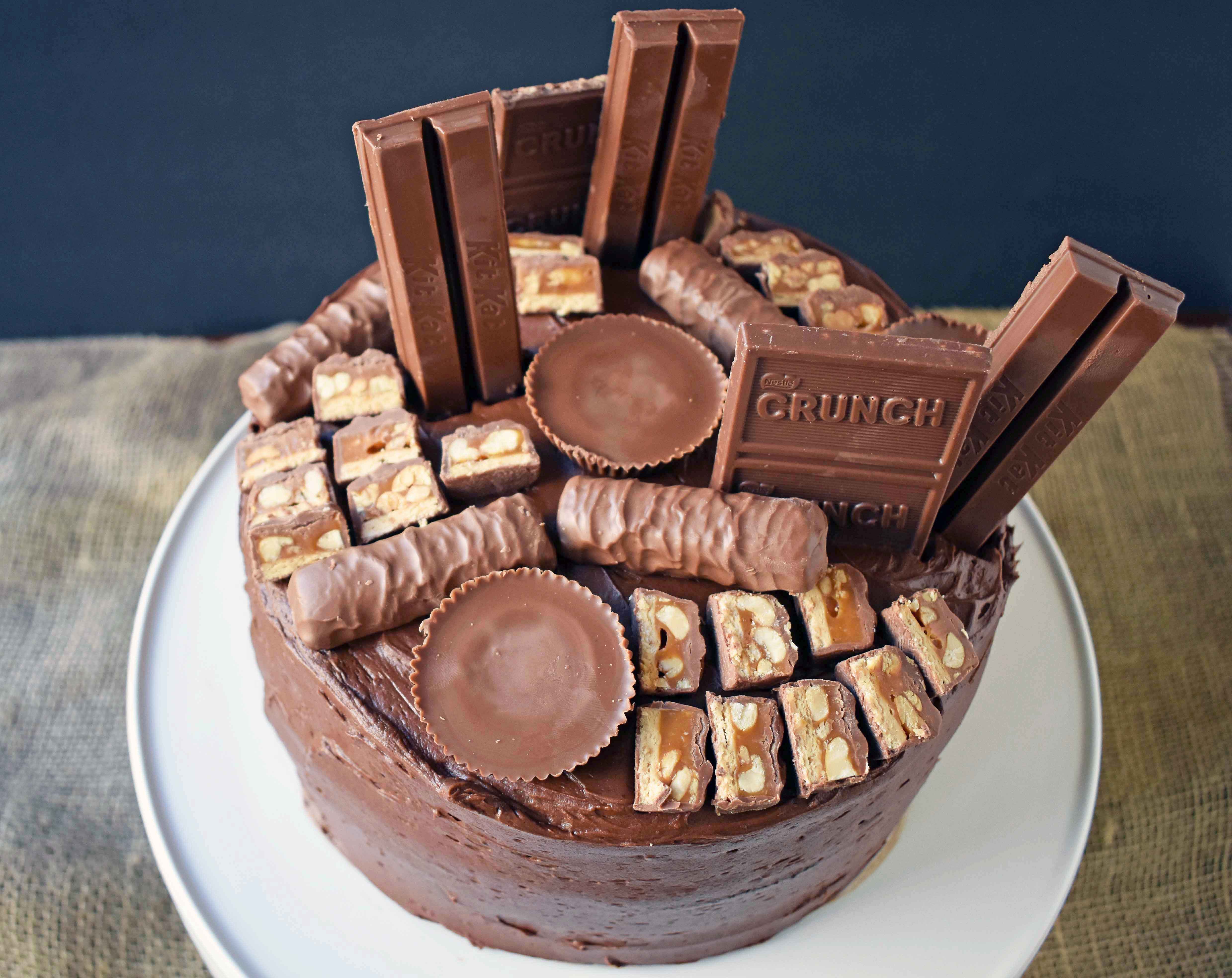 Candy Bar Stash Chocolate Cake by Modern Honey. Perfect chocolate cake topped with chocolate buttercream and the most popular candy bars. It's the ultimate Chocolate Candy Bar Cake.