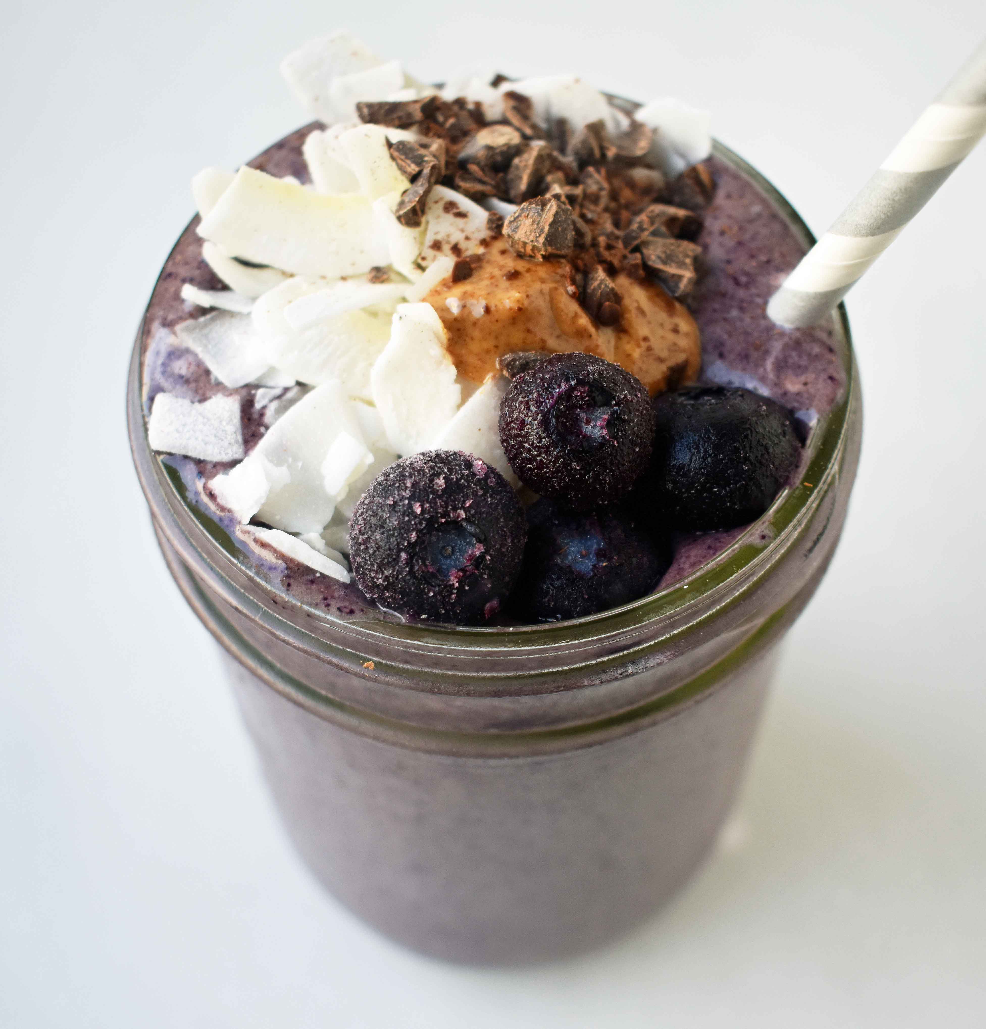 Wild Blueberry Chocolate Coconut Smoothie. Made with chocolate protein powder, coconut milk, blueberries, almond butter, banana, cacao powder. Topped with blueberries, almond butter, and dark chocolate shavings. A craveworthy chocolate coconut protein shake packed with nutrition. www.modernhoney.com