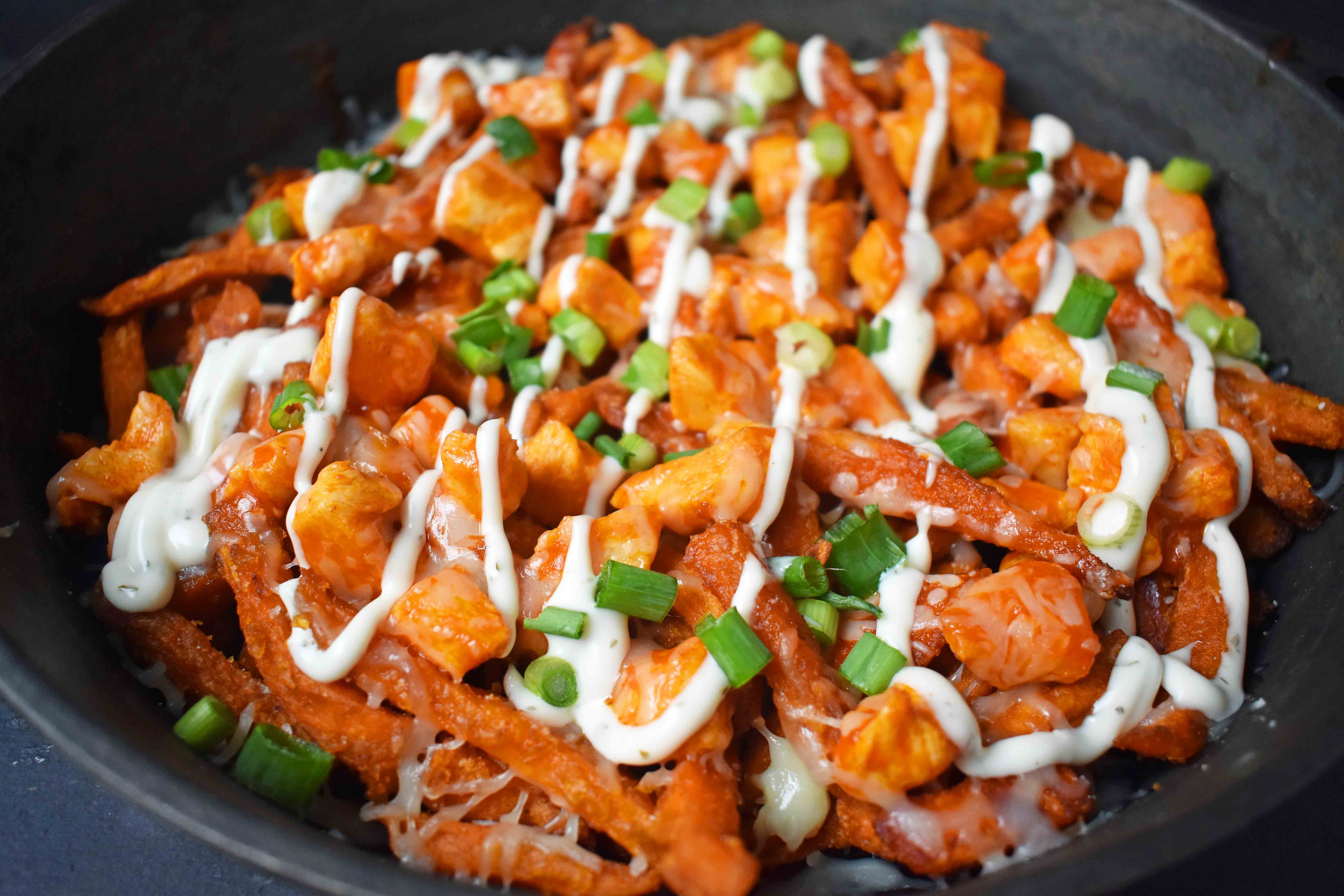 Buffalo Chicken Sweet Potato Fries by Modern Honey. Crisp Sweet Potato Fries topped with Buffalo Wing Chicken, Cheese, Green Onions, and Ranch Dressing. 