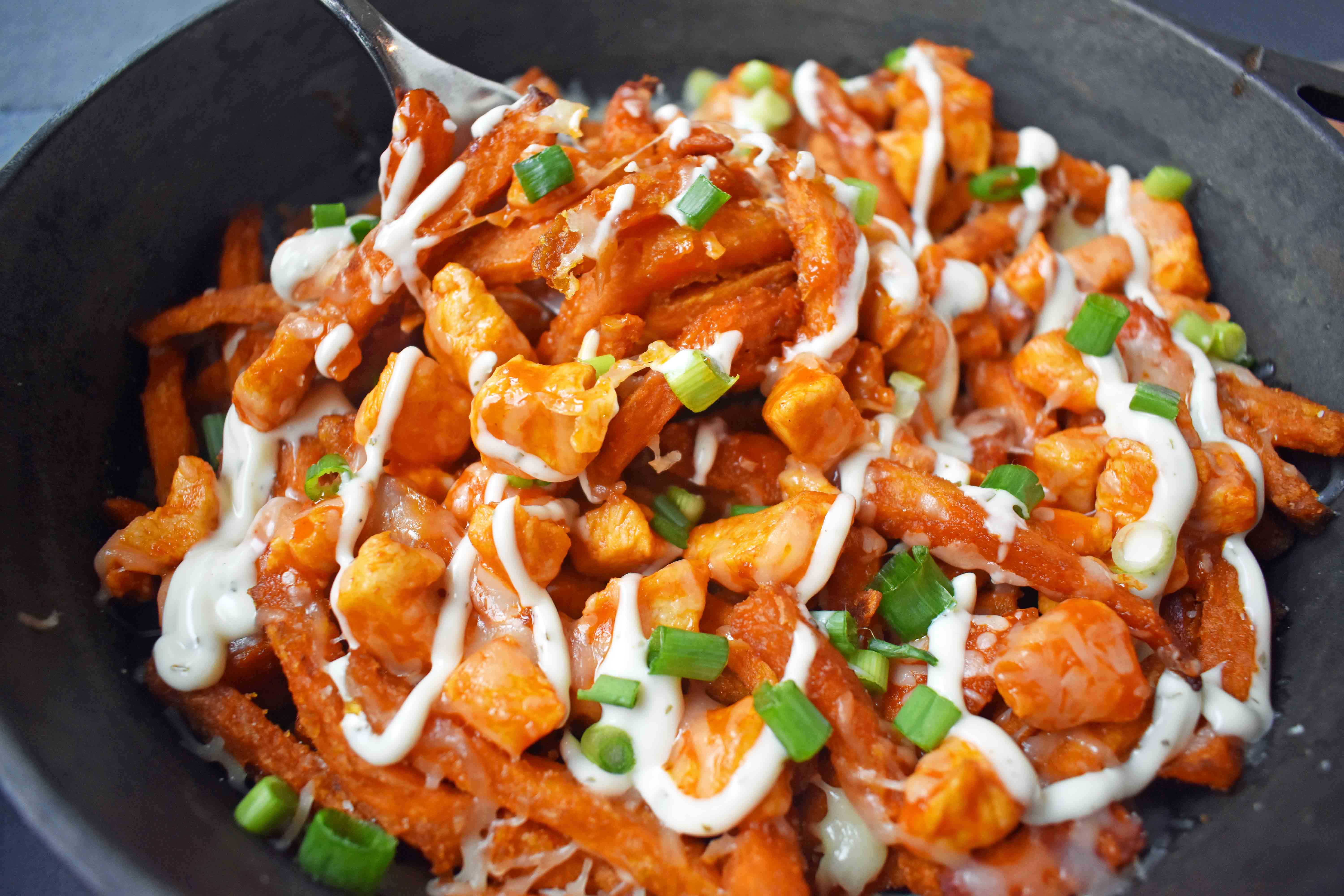 Buffalo Chicken Sweet Potato Fries by Modern Honey. Crisp Sweet Potato Fries topped with Buffalo Wing Chicken, Cheese, Green Onions, and Ranch Dressing. 