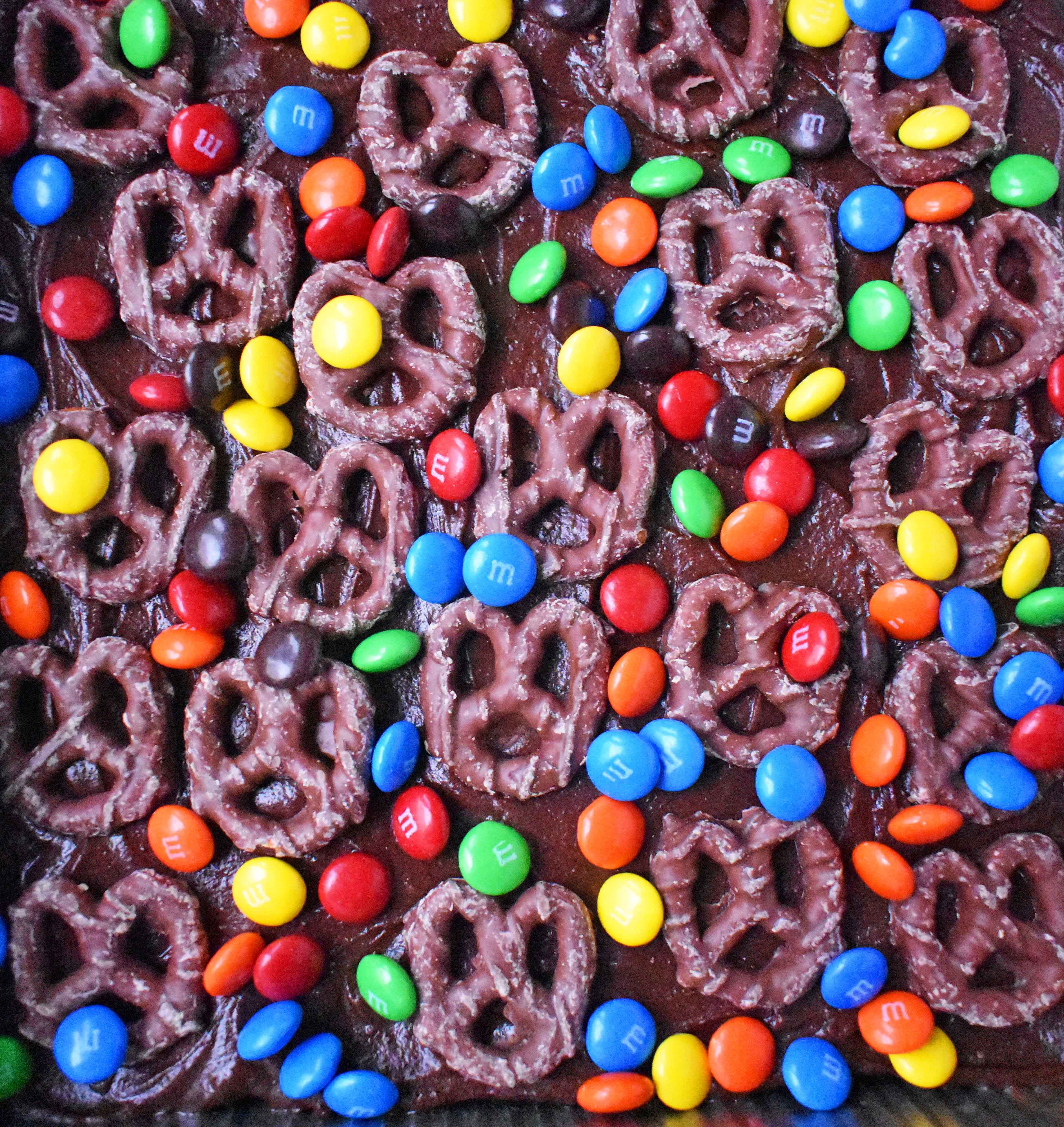 Super Bowl Chocolate Covered Pretzel Brownies. Chewy rich chocolate chunk brownies topped with creamy frosting, chocolate covered pretzels, and M & M's. www.modernhoney.com