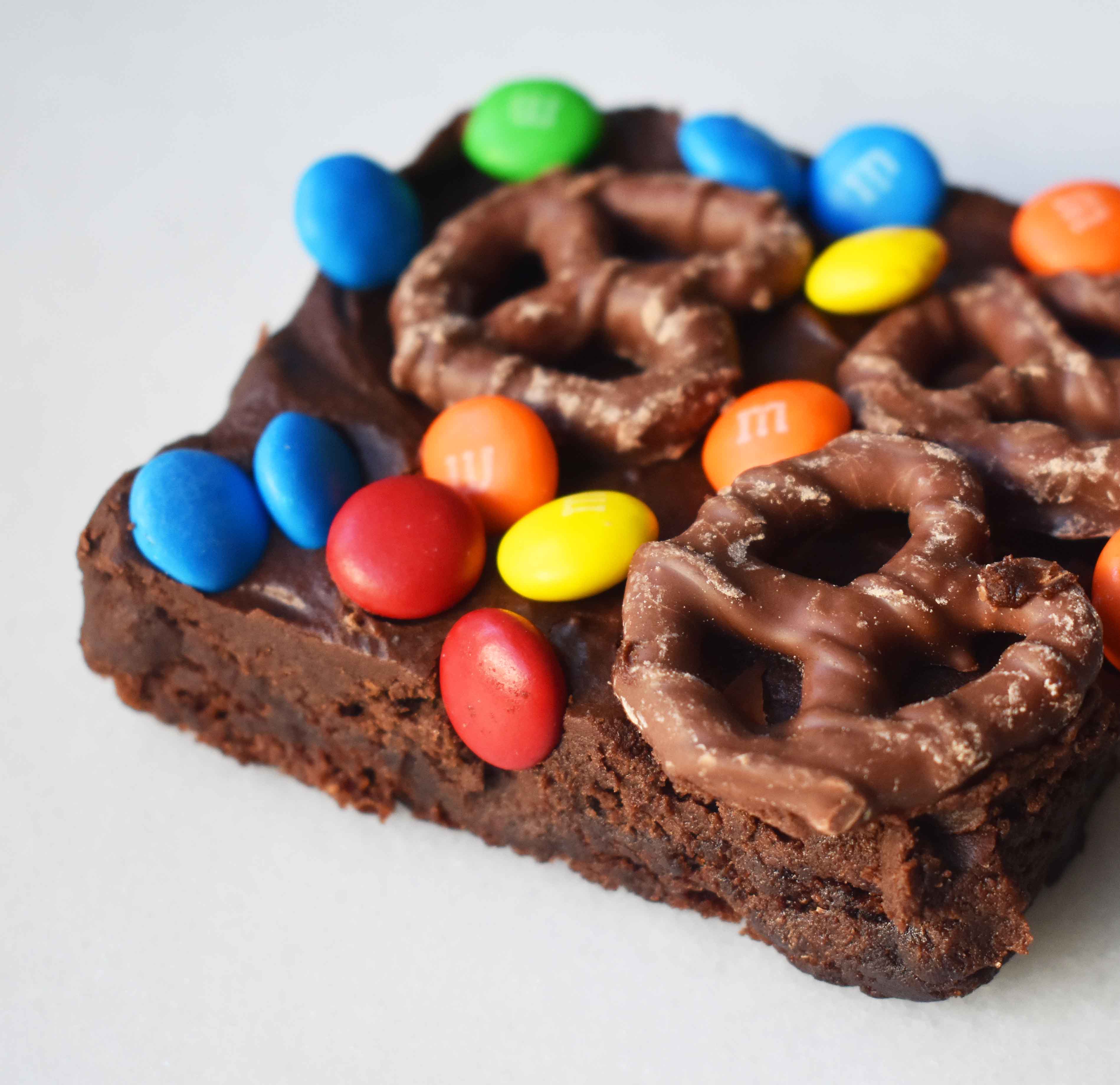 Super Bowl Chocolate Covered Pretzel Brownies. Chewy rich chocolate chunk brownies topped with creamy frosting, chocolate covered pretzels, and M & M's. www.modernhoney.com