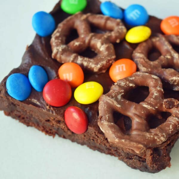 Super Bowl Chocolate Covered Pretzel Brownies. Chewy rich chocolate chunk brownies topped with creamy frosting, chocolate covered pretzels, and M & M's. www.modernhoney.com