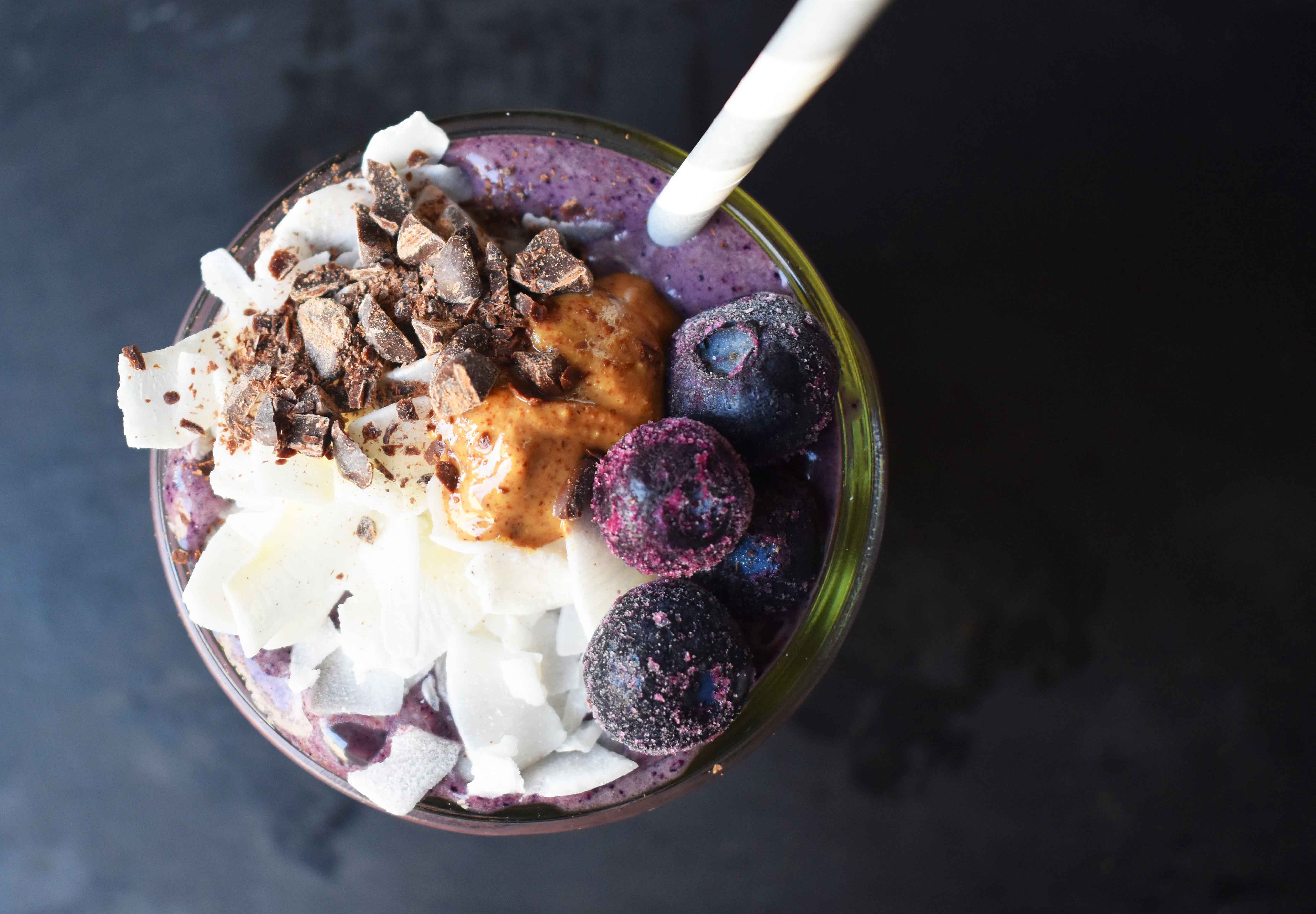 Wild Blueberry Chocolate Coconut Smoothie. Made with chocolate protein powder, coconut milk, blueberries, almond butter, banana, cacao powder. Topped with blueberries, almond butter, and dark chocolate shavings. A craveworthy chocolate coconut protein shake packed with nutrition. www.modernhoney.com