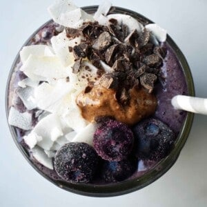 Wild Blueberry Chocolate Coconut Smoothie. Made with chocolate protein powder, coconut milk, blueberries, almond butter, banana, cacao powder. Topped with blueberries, almond butter, and dark chocolate shavings. A craveworthy chocolate coconut protein shake packed with nutrition. www.modernhoney.com