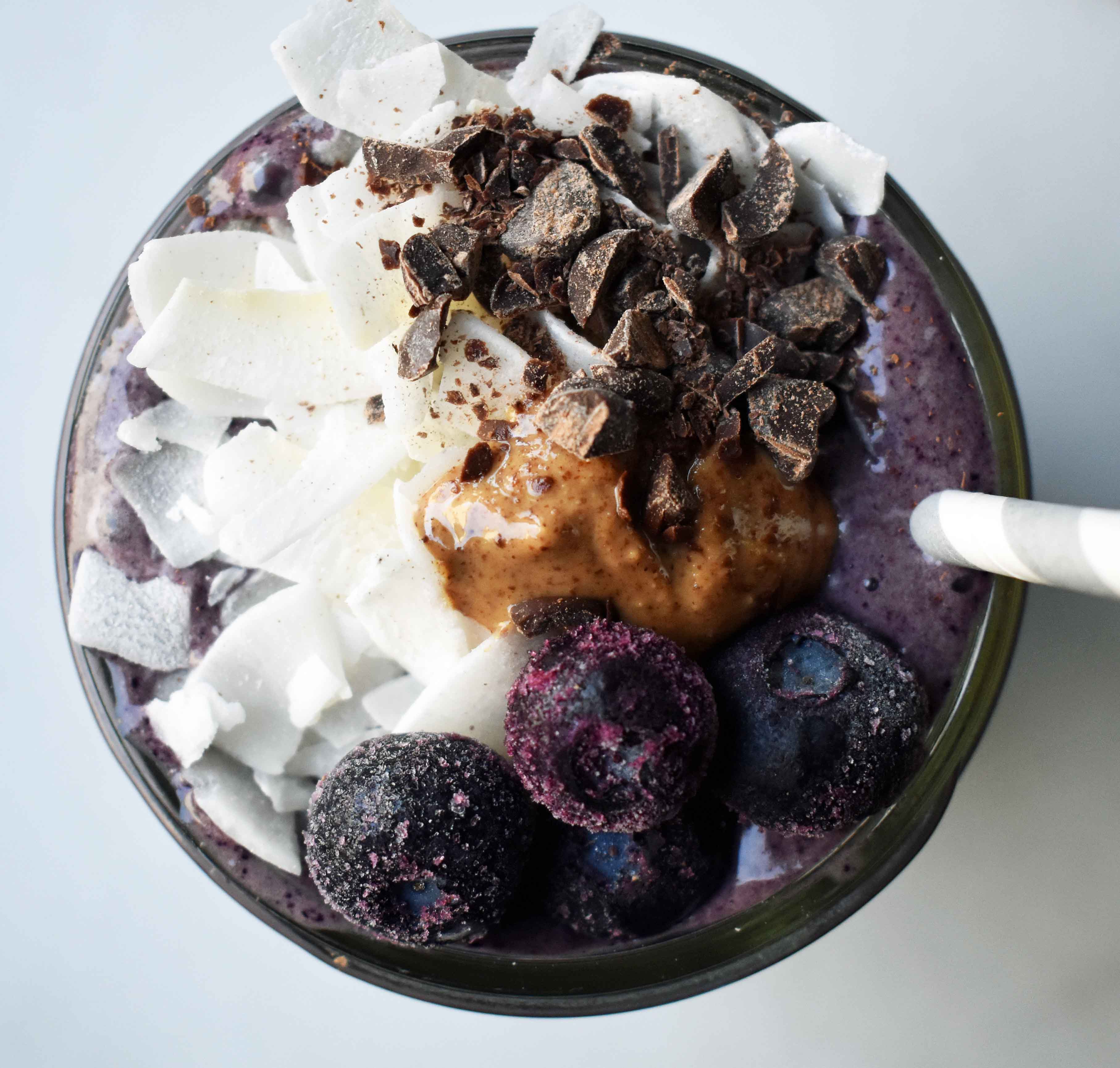 Wild Blueberry Chocolate Coconut Smoothie. Made with chocolate protein powder, coconut milk, blueberries, almond butter, banana, cacao powder. Topped with blueberries, almond butter, and dark chocolate shavings. A craveworthy chocolate coconut protein shake packed with nutrition. www.modernhoney.com