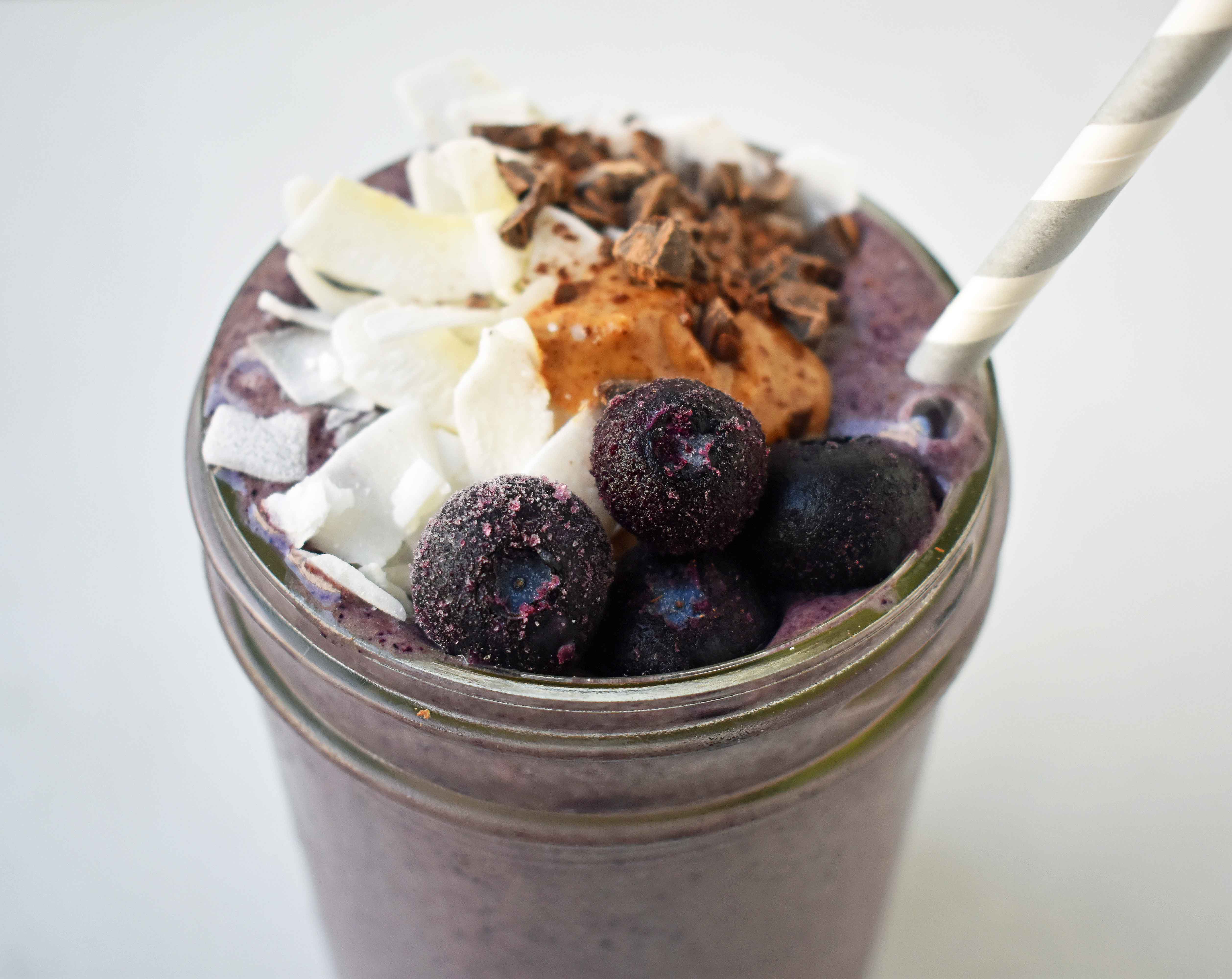 Wild Blueberry Chocolate Coconut Smoothie. Made with chocolate protein powder, coconut milk, blueberries, almond butter, banana, cacao powder. Topped with blueberries, almond butter, and dark chocolate shavings. A craveworthy chocolate coconut protein shake packed with nutrition. www.modernhoney.com