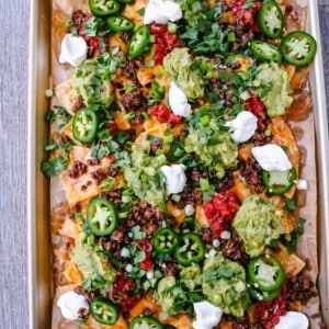 Ground Beef Nachos Recipe Seasoned ground beef with crispy tortilla chips, Mexican cheeses, fresh guacamole, sour cream, jalapenos, fresh salsa, green onions, and cilantro make the best beef nachos!