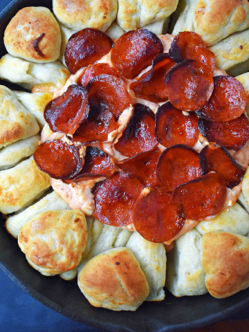 Pepperoni Pizza Dip with Pizza Crust Dippers by Modern Honey. Creamy pizza dip topped with crispy pepperoni and baked with garlic butter pizza rolls. All baked in a cast iron skillet. www.modernhoney.com