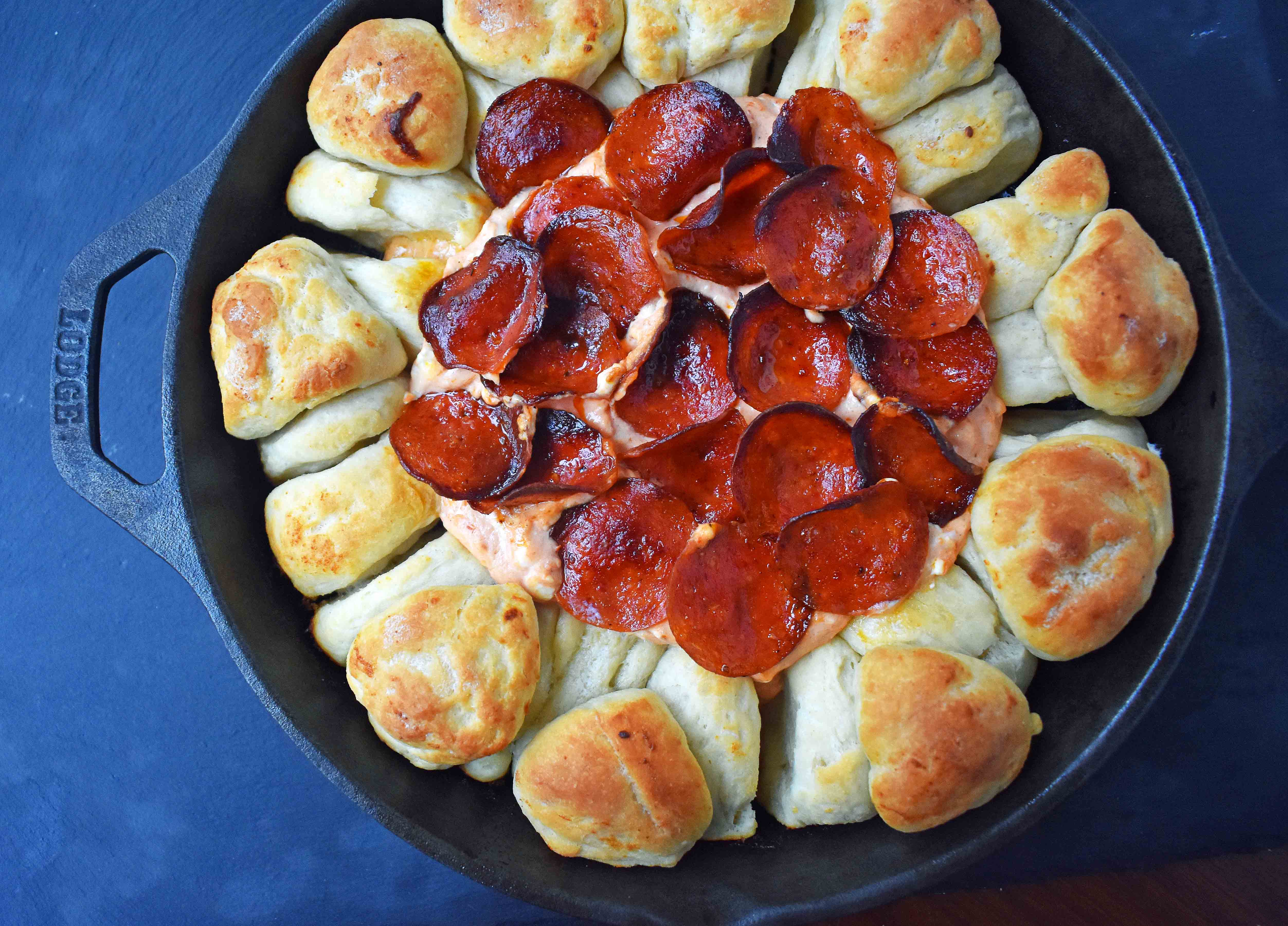 Pepperoni Pizza Dip with Pizza Crust Dippers by Modern Honey. Creamy pizza dip topped with crispy pepperoni and baked with garlic butter pizza rolls. All baked in a cast iron skillet. www.modernhoney.com