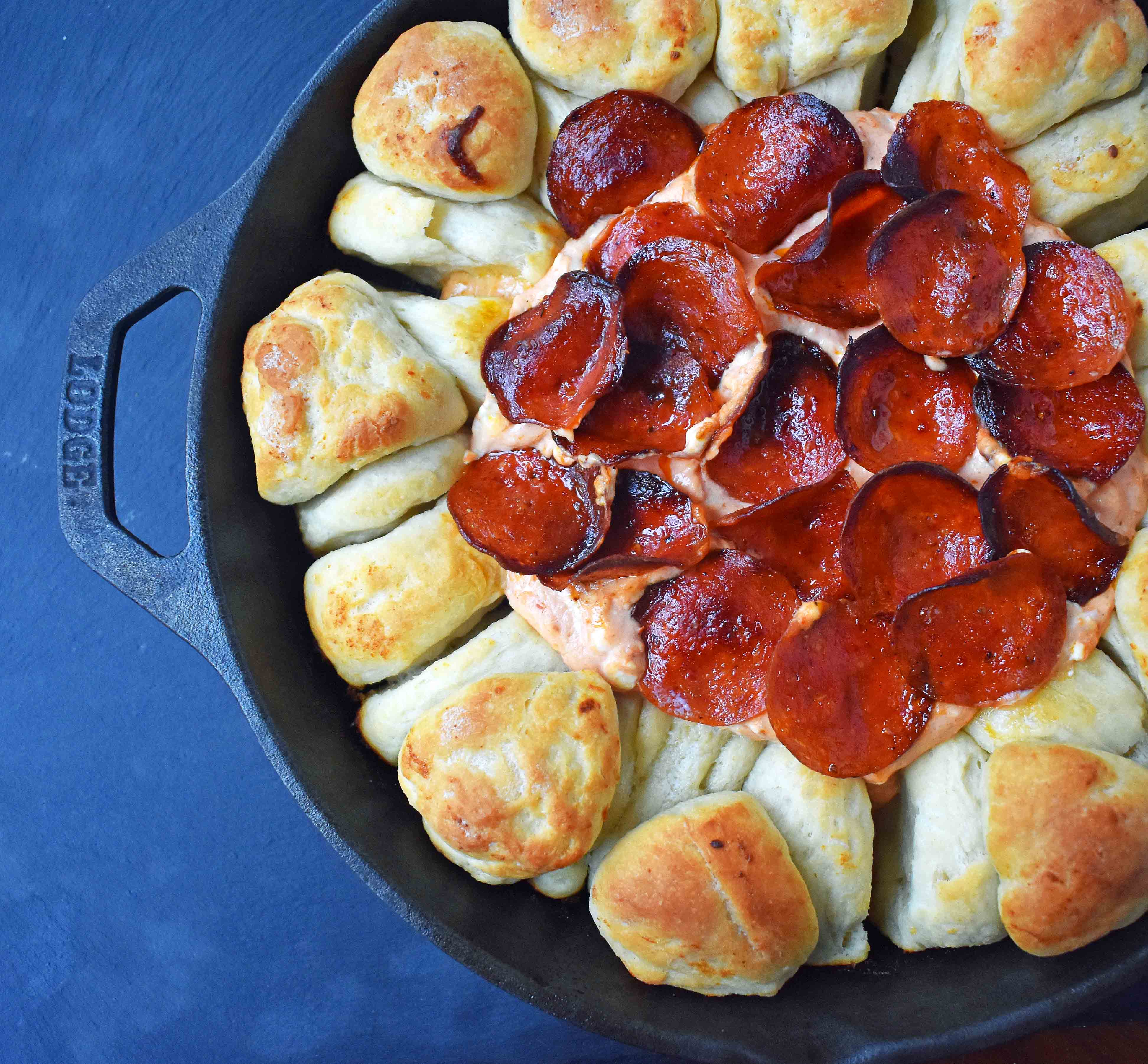 Pepperoni Pizza Dip with Pizza Crust Dippers by Modern Honey. Creamy pizza dip topped with crispy pepperoni and baked with garlic butter pizza rolls. All baked in a cast iron skillet. www.modernhoney.com