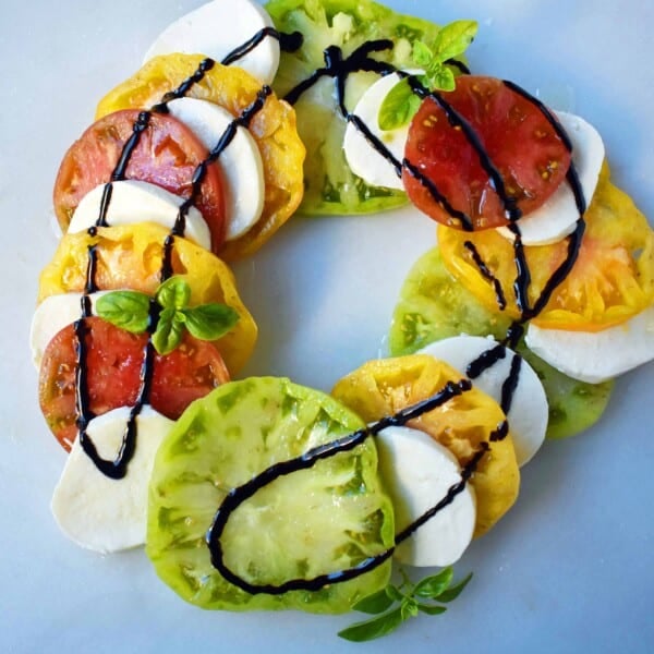 Heirloom Tomato Caprese Salad by Modern Honey. Garden Heirloom tomatoes layered with fresh mozzarella slices, extra virgin olive oil, balsamic glaze, salt, and fresh basil. A beautiful and healthy appetizer. www.modernhoney.com