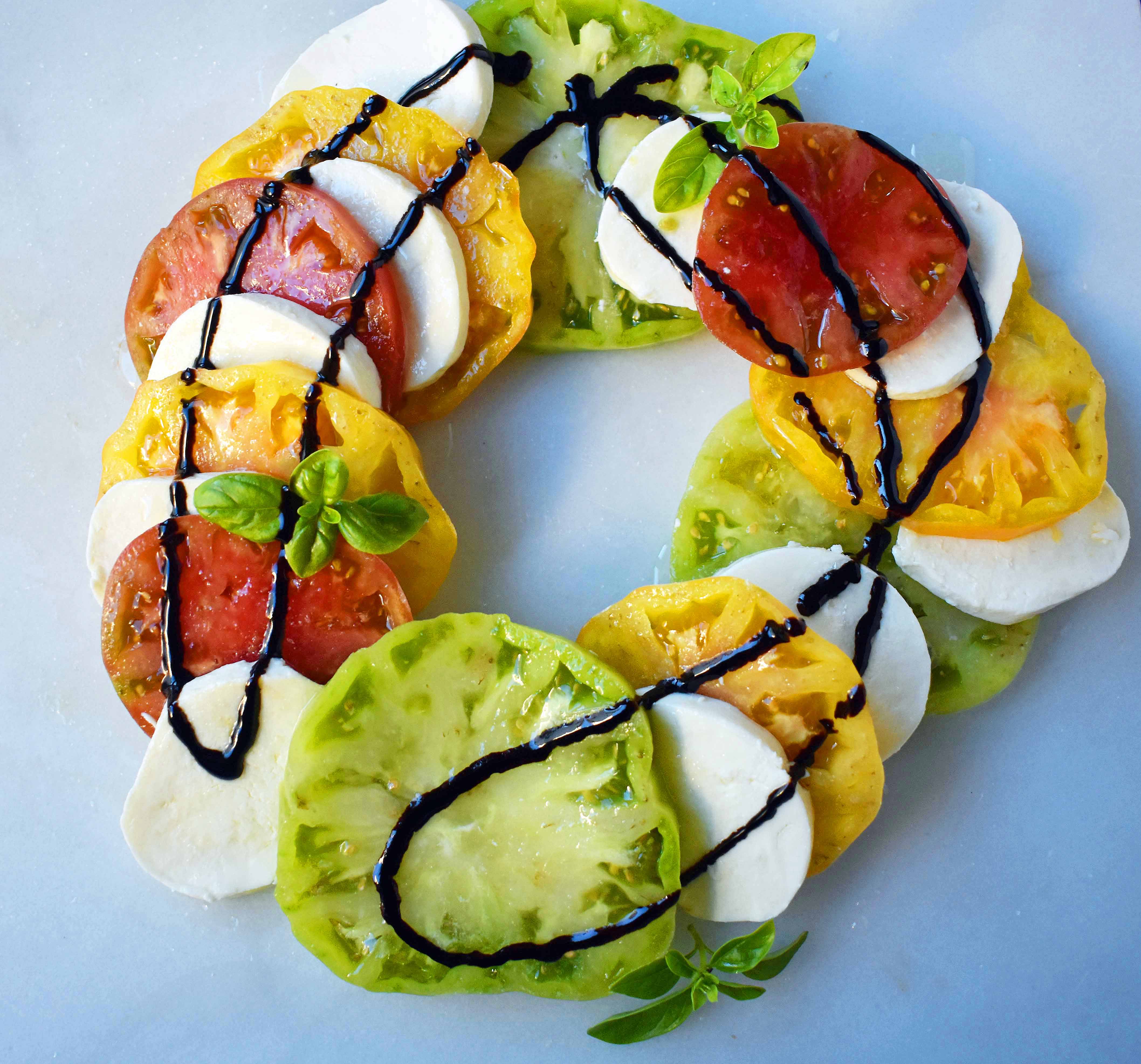 Heirloom Tomato Caprese Salad by Modern Honey. Garden Heirloom tomatoes layered with fresh mozzarella slices, extra virgin olive oil, balsamic glaze, salt, and fresh basil. A beautiful and healthy appetizer. www.modernhoney.com