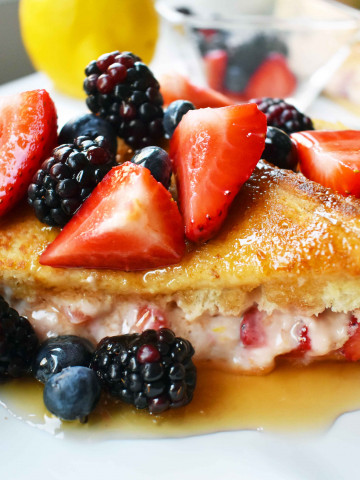 Strawberries and Cream French Toast. Sweet cream cheese, jam and fresh strawberries stuffed between two pieces of soft Texas toast. Dipped into a rich custard batter and cooked until golden brown in skillet. Gourmet french toast made in less than 15 minutes. Perfect topped with fresh berries and homemade whipped cream. www.modernhoney.com
