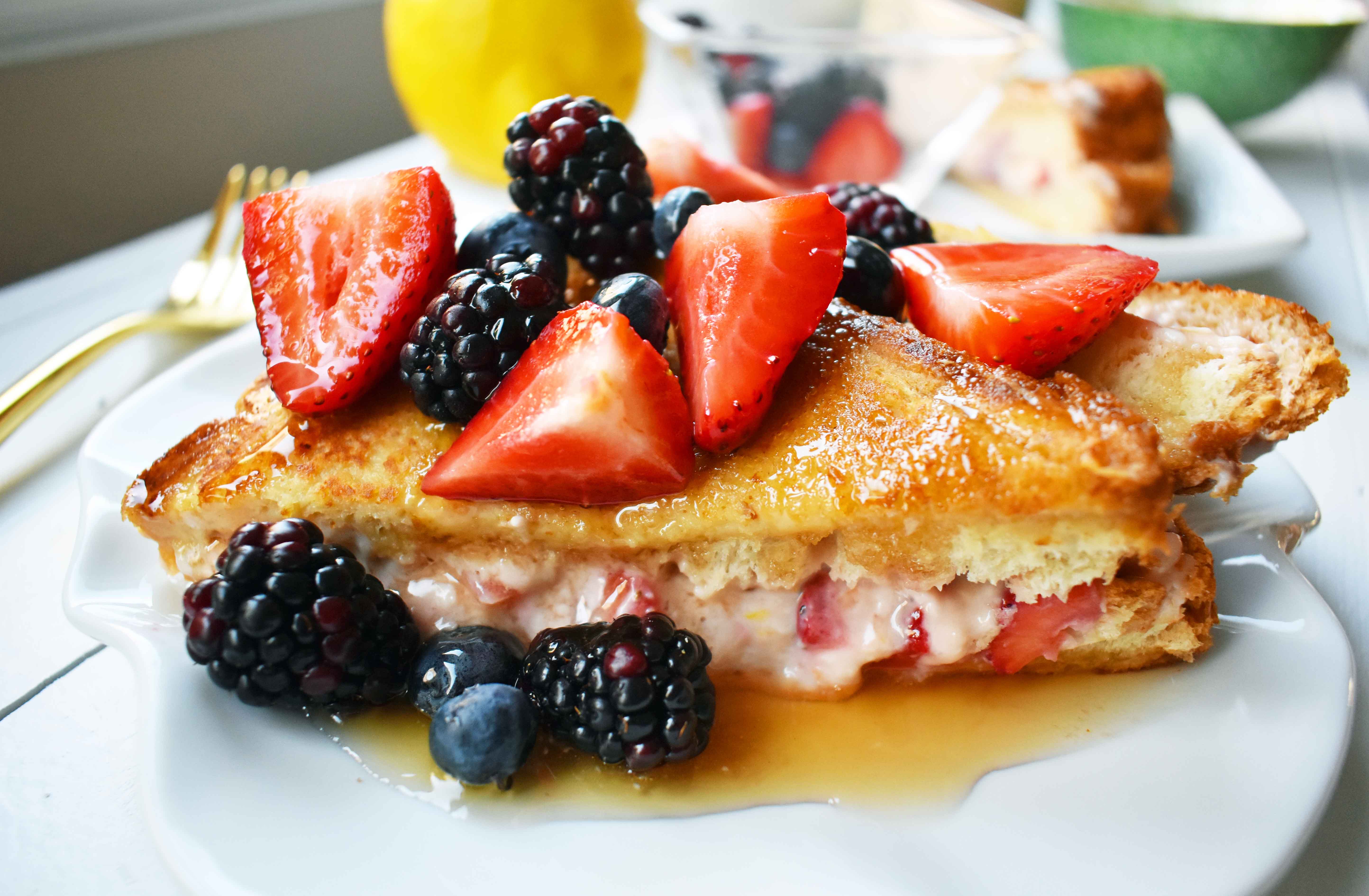 Strawberries and Cream French Toast. Sweet cream cheese, jam and fresh strawberries stuffed between two pieces of soft Texas toast. Dipped into a rich custard batter and cooked until golden brown in skillet. Gourmet french toast made in less than 15 minutes. Perfect topped with fresh berries and homemade whipped cream. www.modernhoney.com