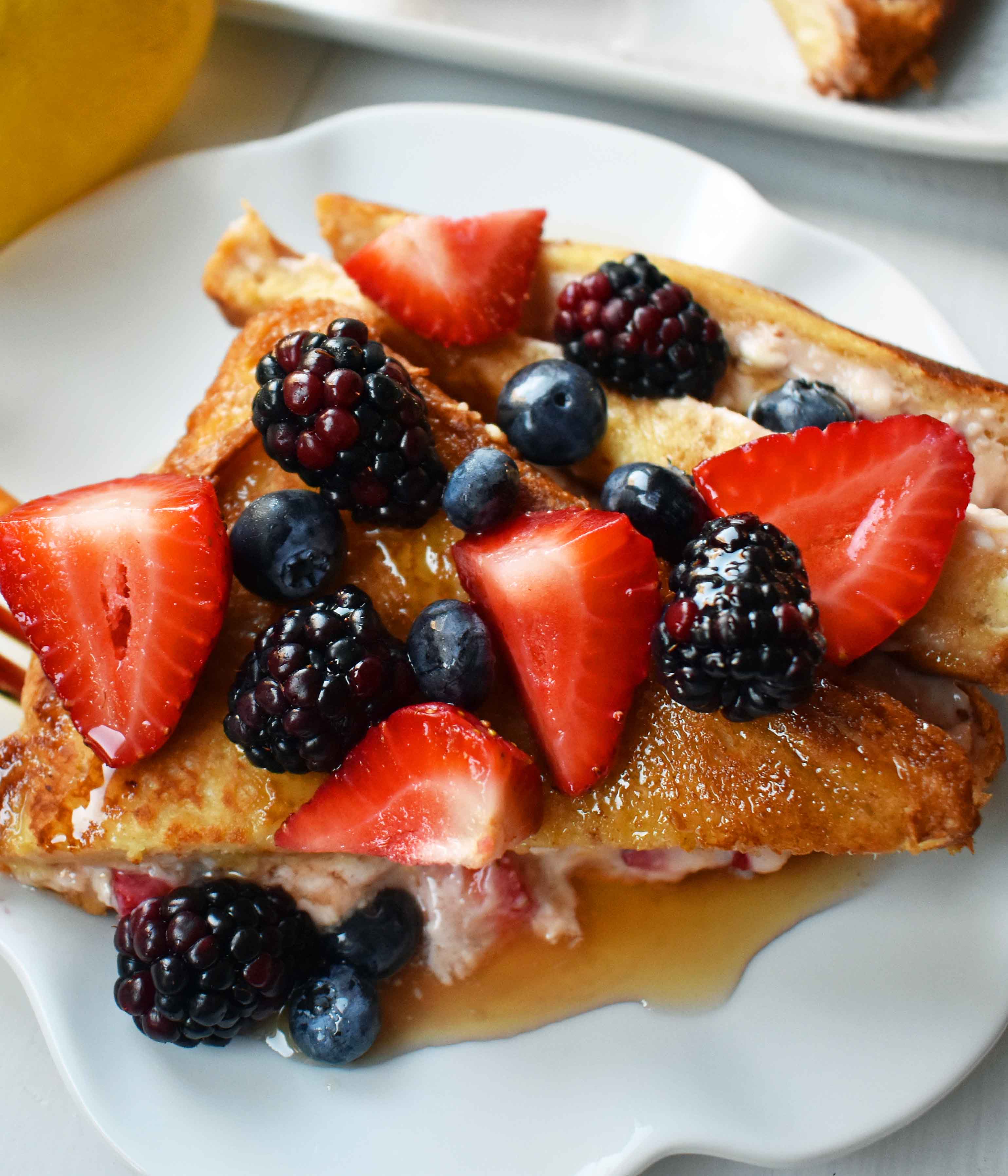 Strawberries and Cream French Toast. Sweet cream cheese, jam and fresh strawberries stuffed between two pieces of soft Texas toast. Dipped into a rich custard batter and cooked until golden brown in skillet. Gourmet french toast made in less than 15 minutes. Perfect topped with fresh berries and homemade whipped cream. www.modernhoney.com