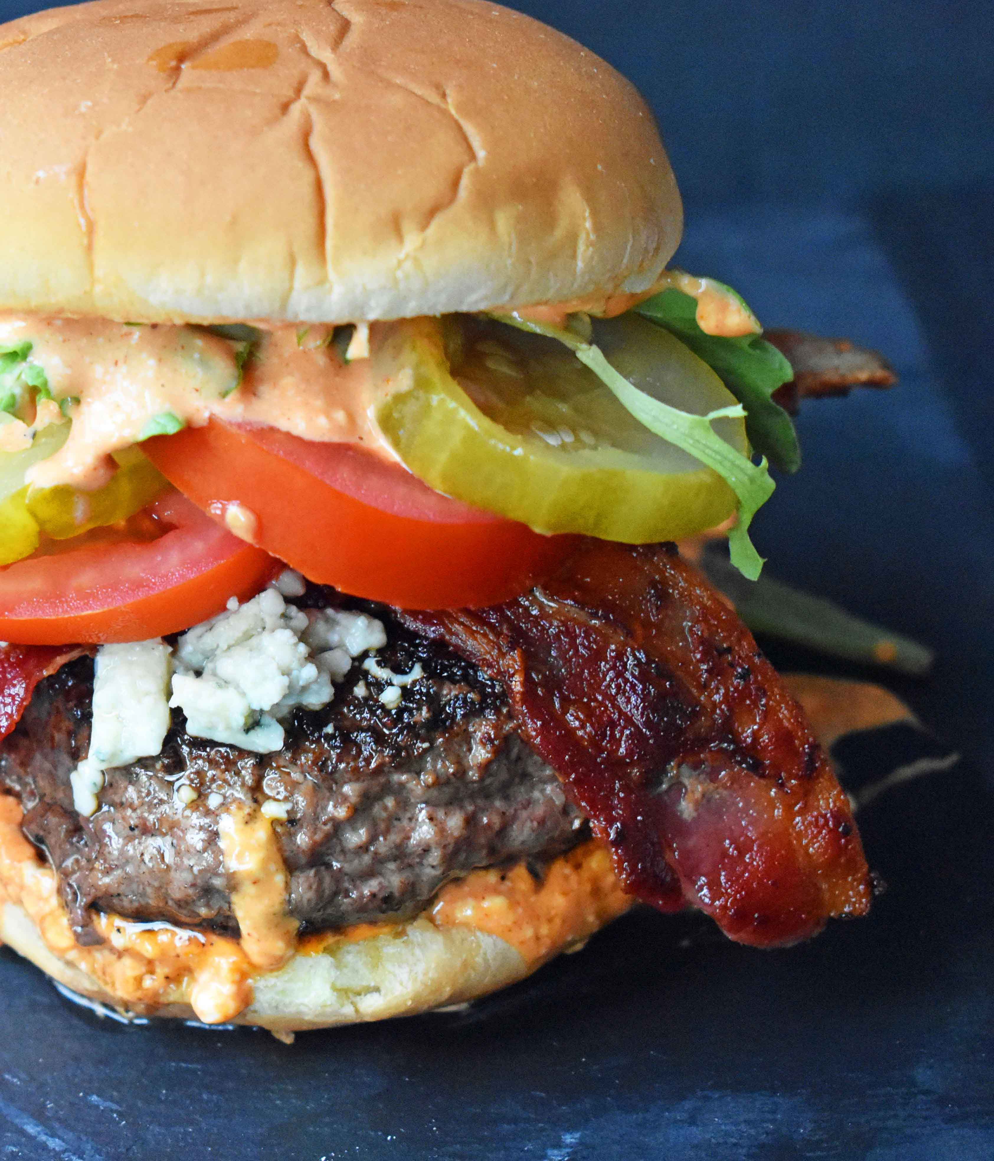 Dragonslayer Burger. Beef with blue cheese, crispy bacon, juicy tomatoes, crunchy pickles, spring mix, and buffalo ranch sauce. www.modernhoney.com