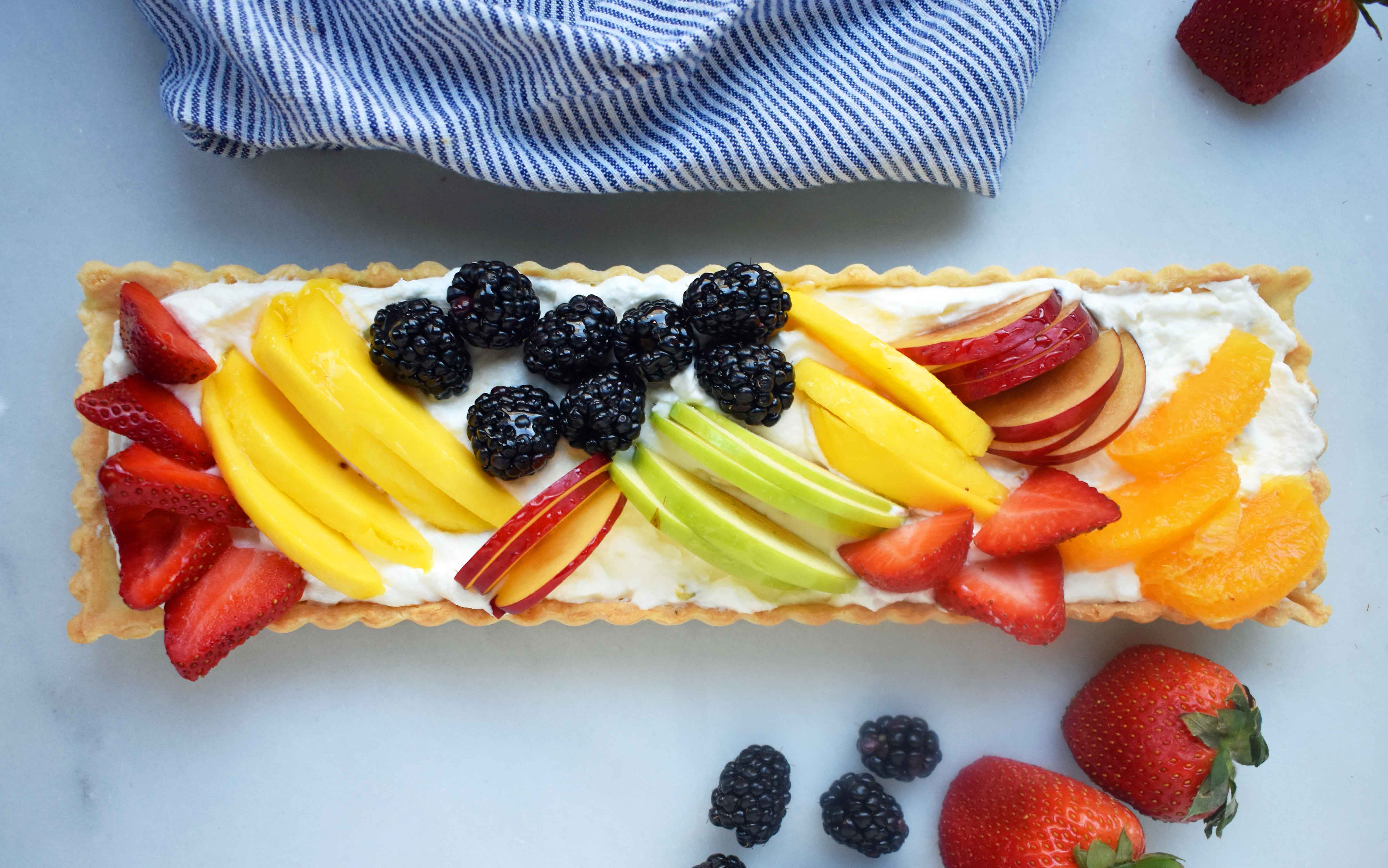 Lemon Cream Filled Fruit Tart. Buttery, flaky pie crust baked in tart pan and filled with homemade lemon cream and topped with sliced fresh fruit. A beautiful Spring and Summer dessert that everyone loves. www.modernhoney.com