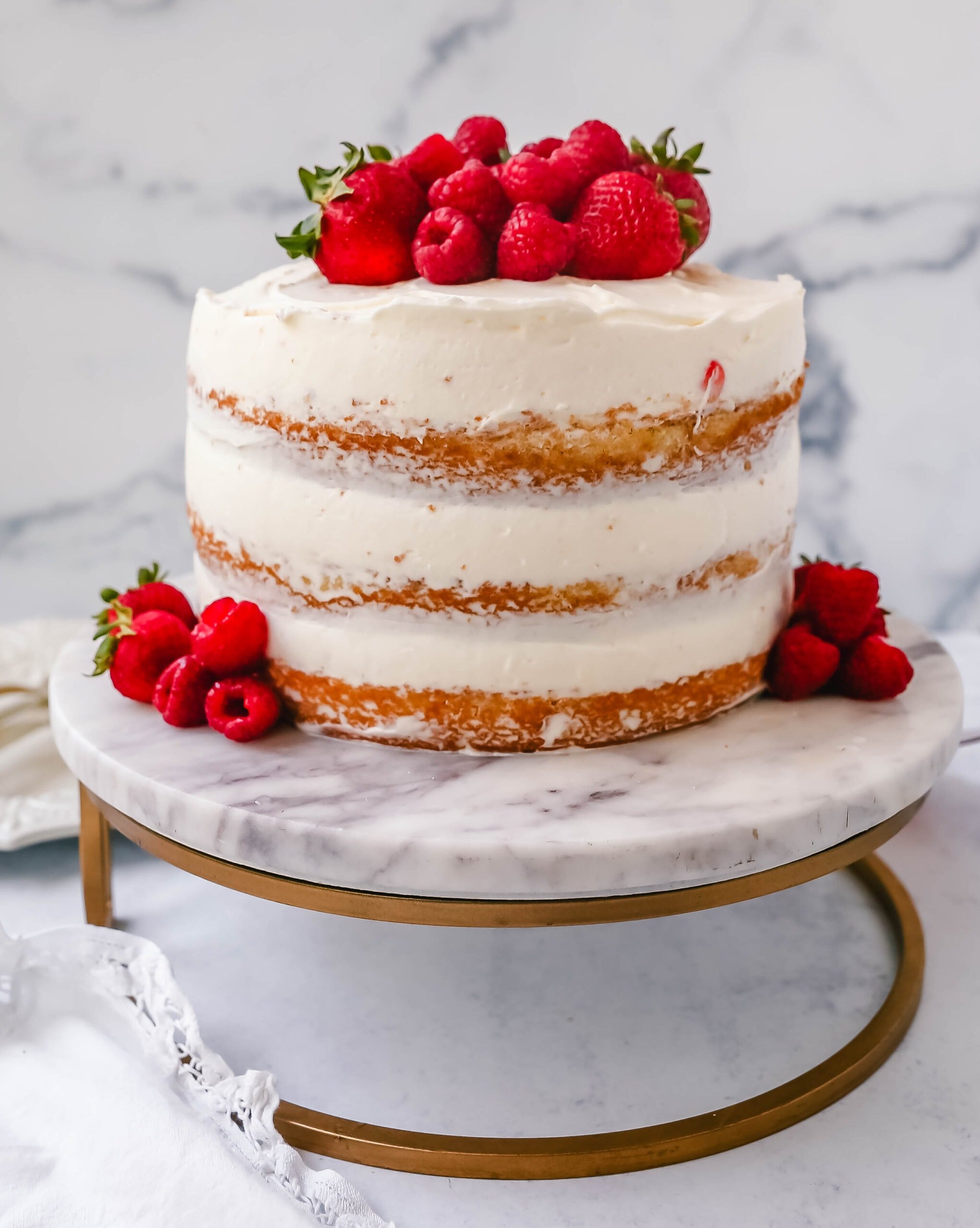 Homemade yellow cake layered with fluffy cream cheese whipped cream frosting and fresh berries. 