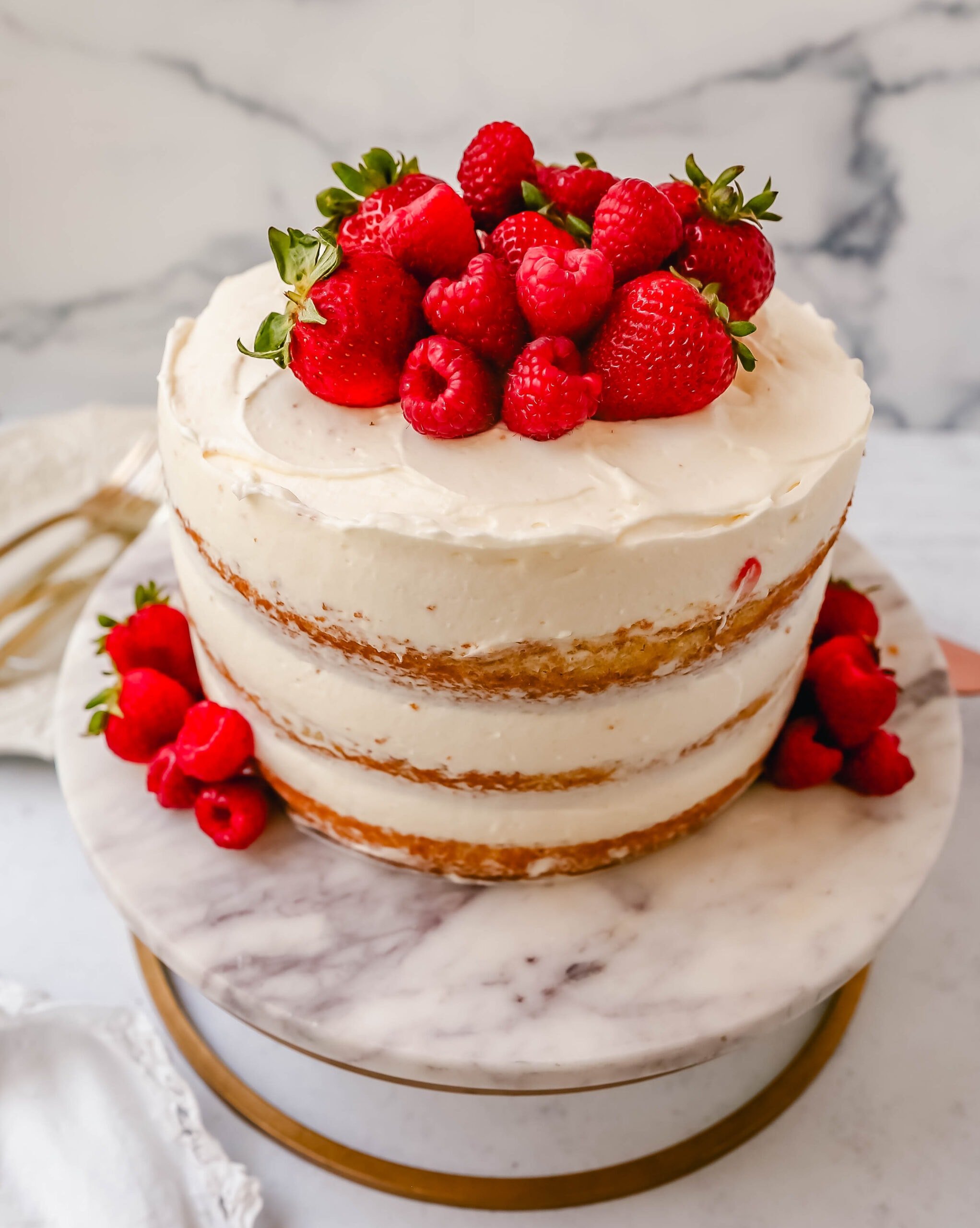 Homemade yellow cake layered with fluffy cream cheese whipped cream frosting and fresh berries. 