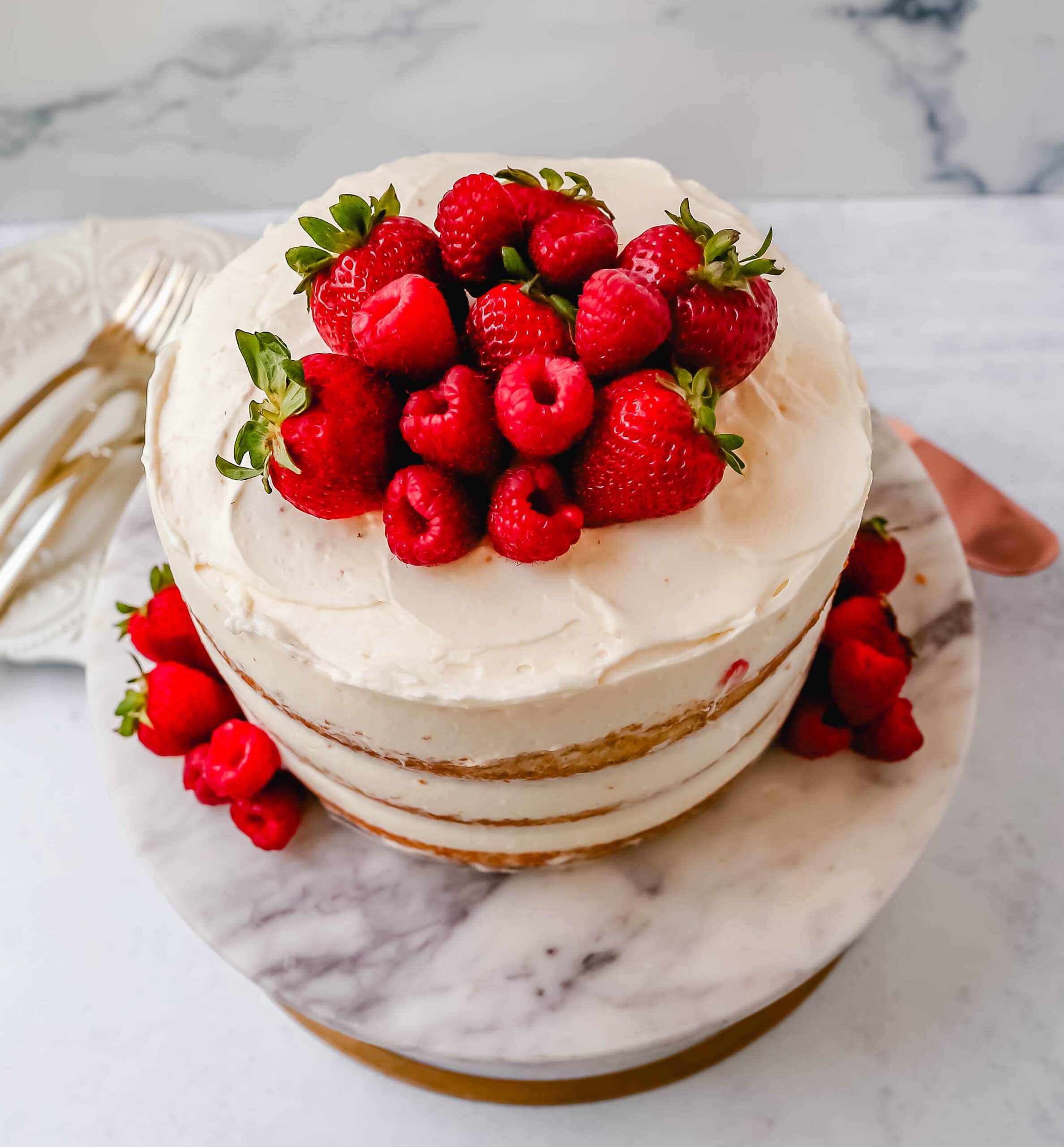 Homemade yellow cake layered with fluffy cream cheese whipped cream frosting and fresh berries. 