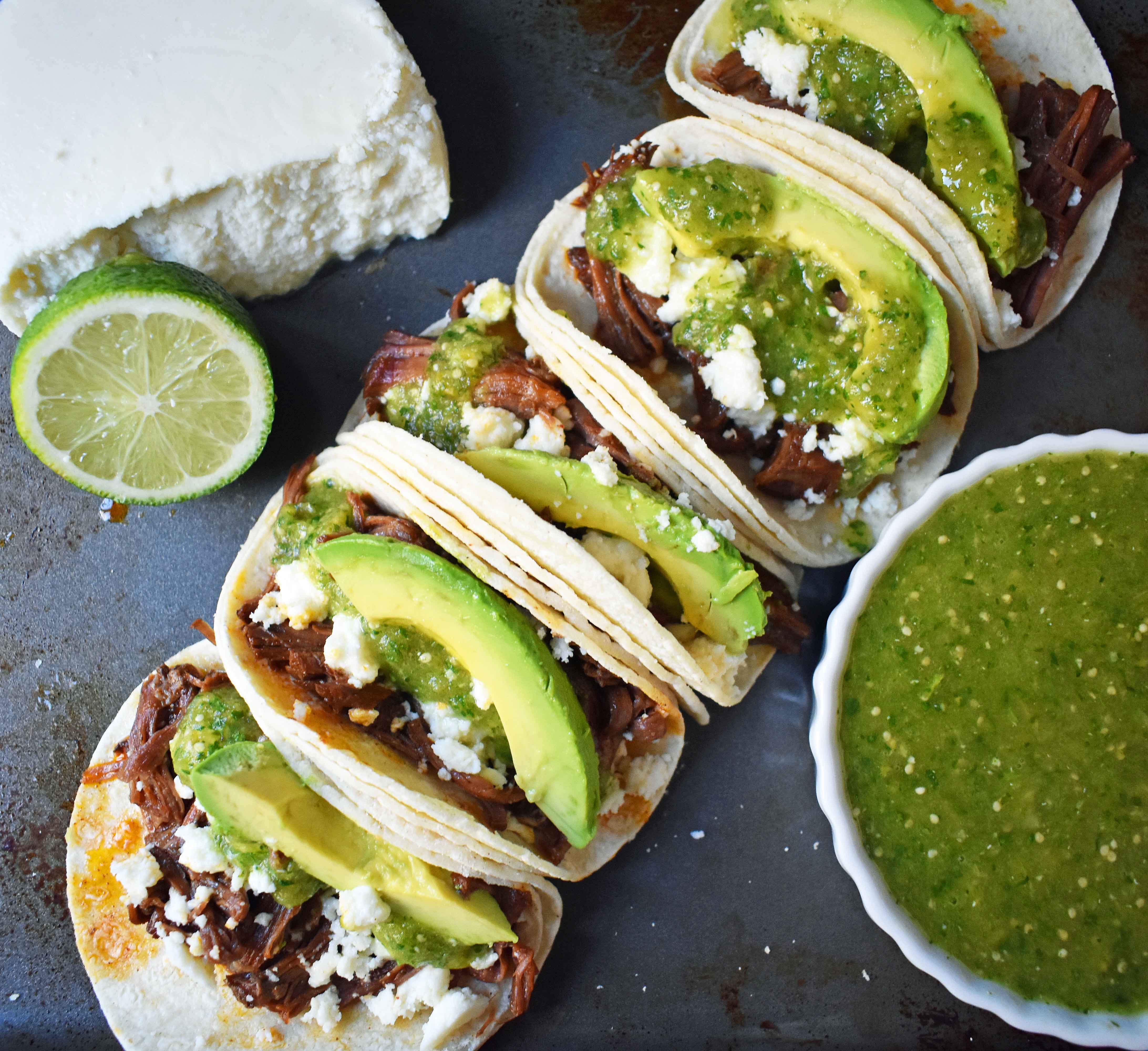 Slow Cooker Beef Barbacoa Tacos with Homemade Tomatillo Salsa. Tender spicy beef barbacoa made in slow cooker and topped with fresh avocado, queso fresco cheese, and homemade tomatillo salsa. www.modernhoney.com