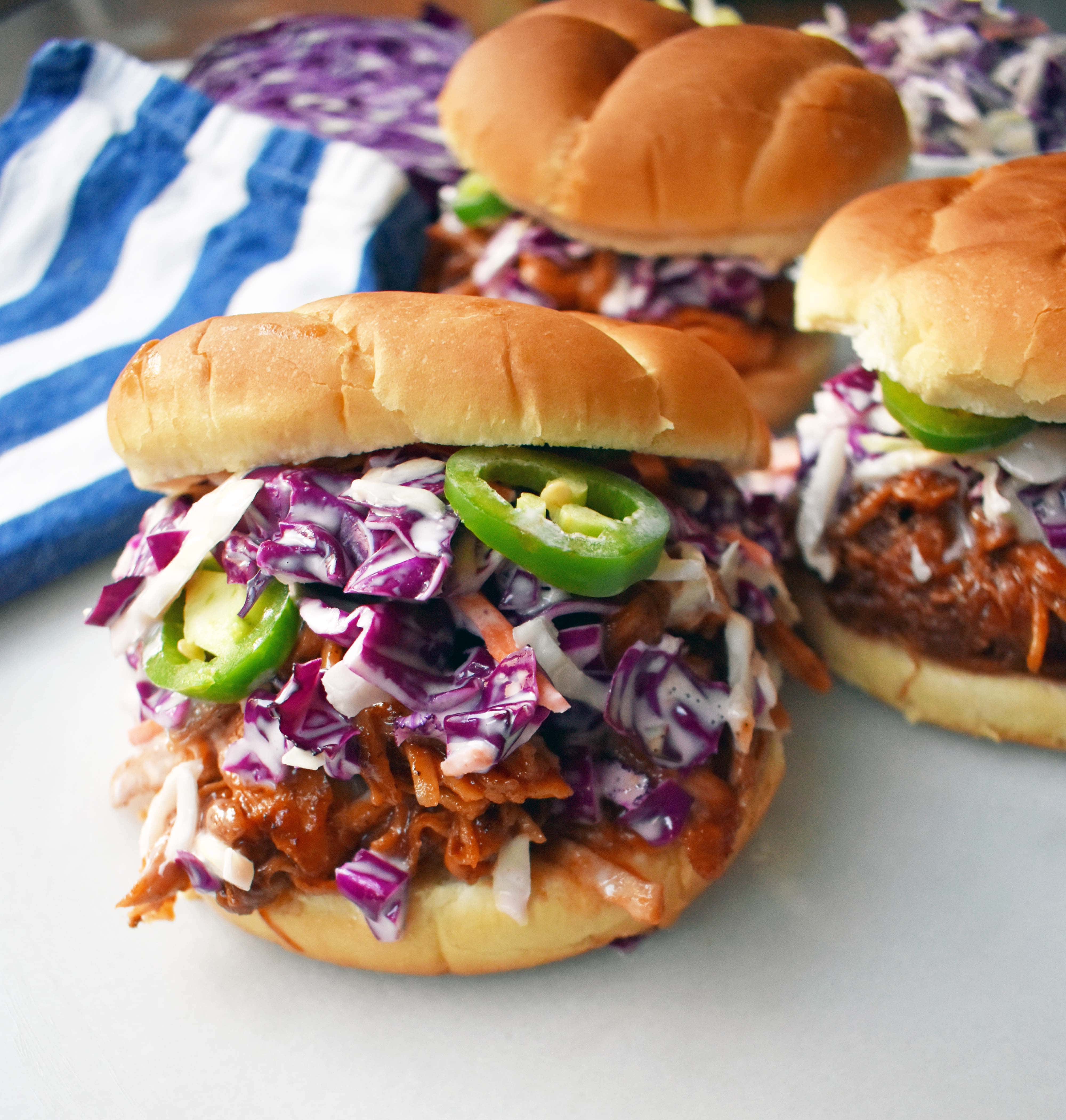 Slow Cooker Dr. Pepper Pulled Pork Sandwich. Slow cooked pork simmered with Dr. Pepper, spices, and BBQ sauce. Topped with homemade coleslaw and fresh jalapenos, all on a soft bun. The perfect BBQ Pulled Pork Sandwich. www.modernhoney.com