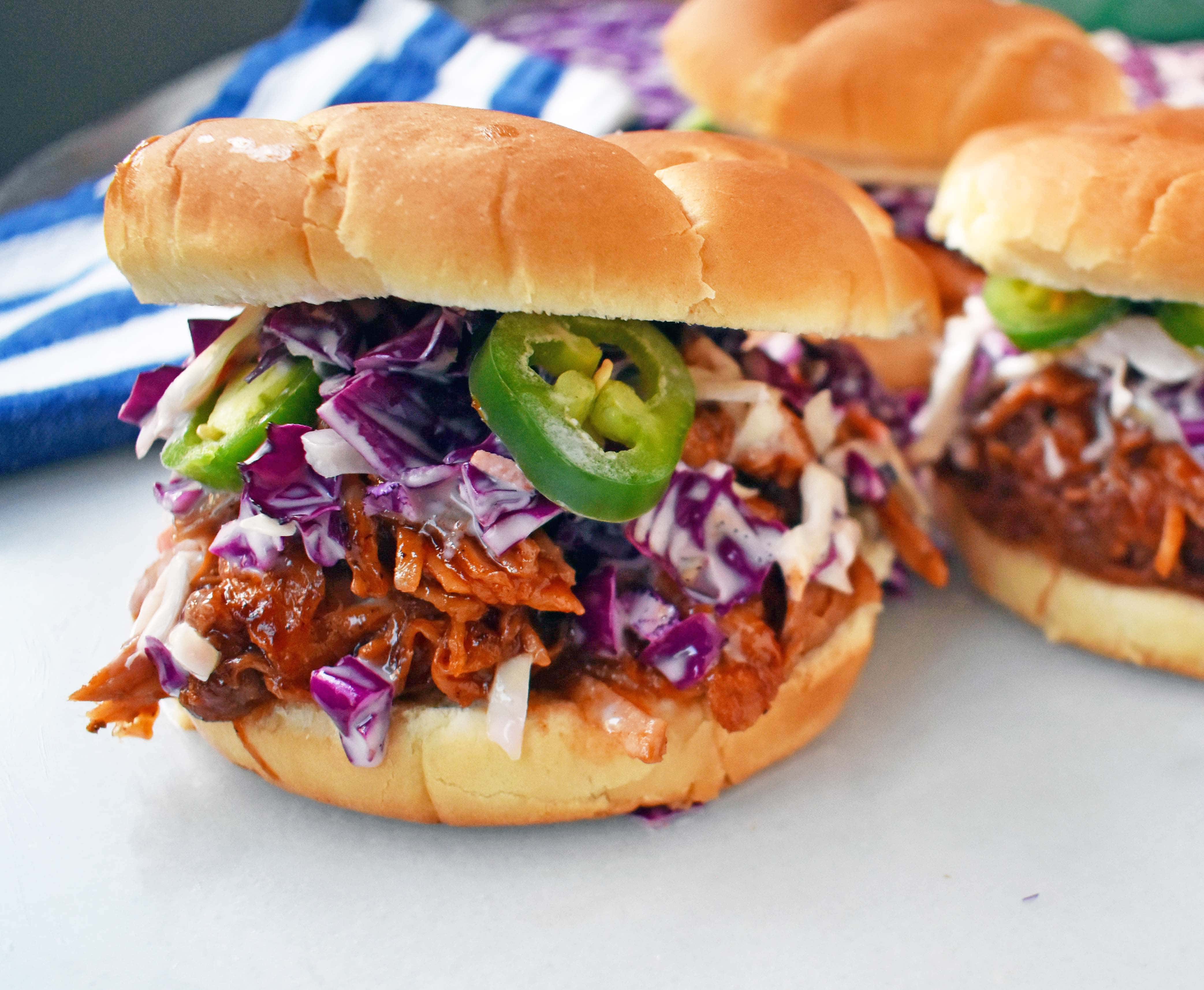 Slow Cooker Dr. Pepper Pulled Pork Sandwich. Hitaasti kypsennettyä sianlihaa haudutetaan Dr. Pepperin, mausteiden ja BBQ-kastikkeen kera. Päällä kotitekoista kaalisalaattia ja tuoreita jalapenoja, kaikki pehmeällä pullalla. Täydellinen BBQ Pulled Pork Sandwich. www.modernhoney.com