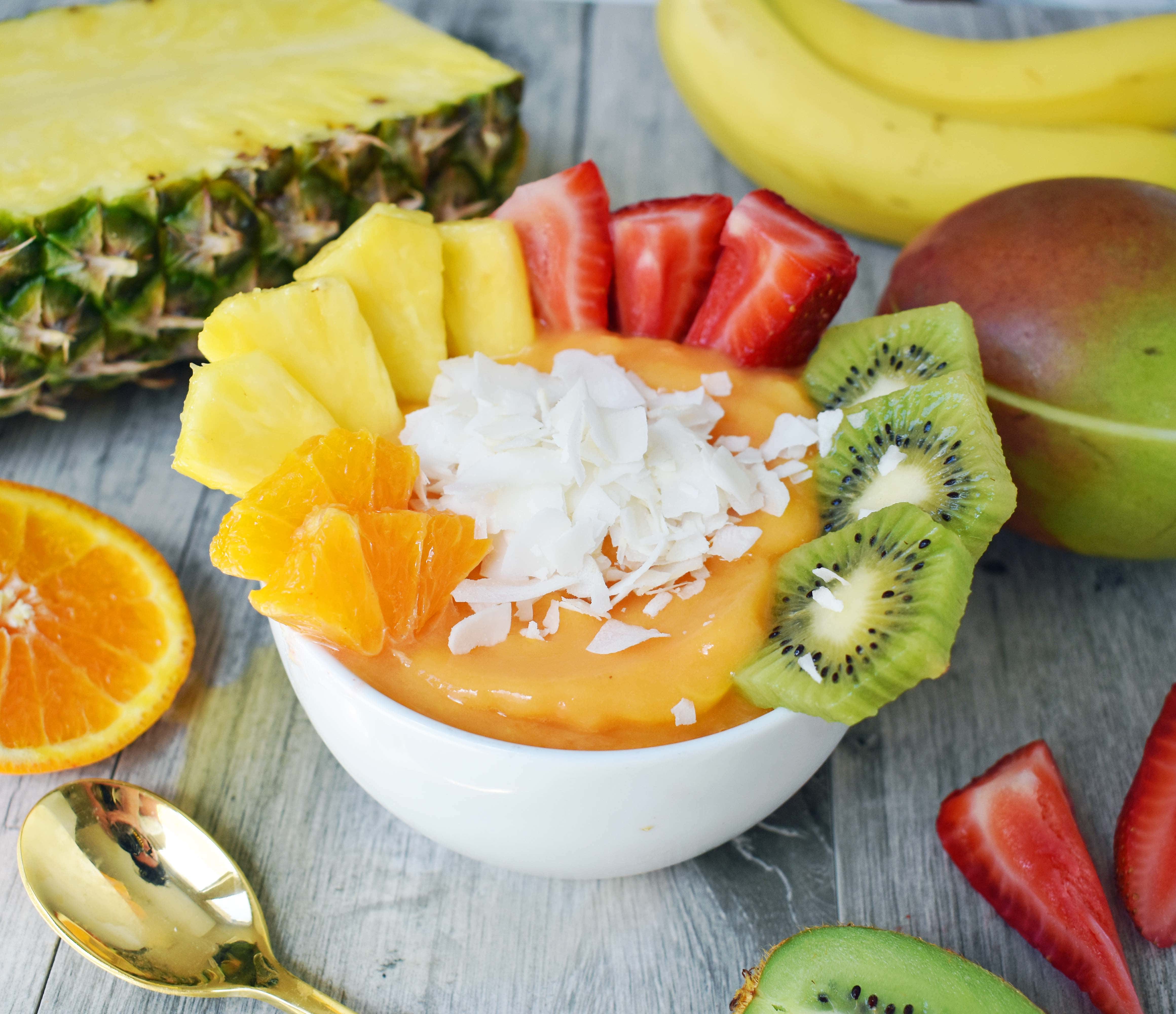 Kissed by Sunshine Smoothie Bowl made with frozen fruits, juice or coconut milk, and topped with fresh fruits, coconut shavings, and granola. A healthy and filling breakfast. www.modernhoney.com