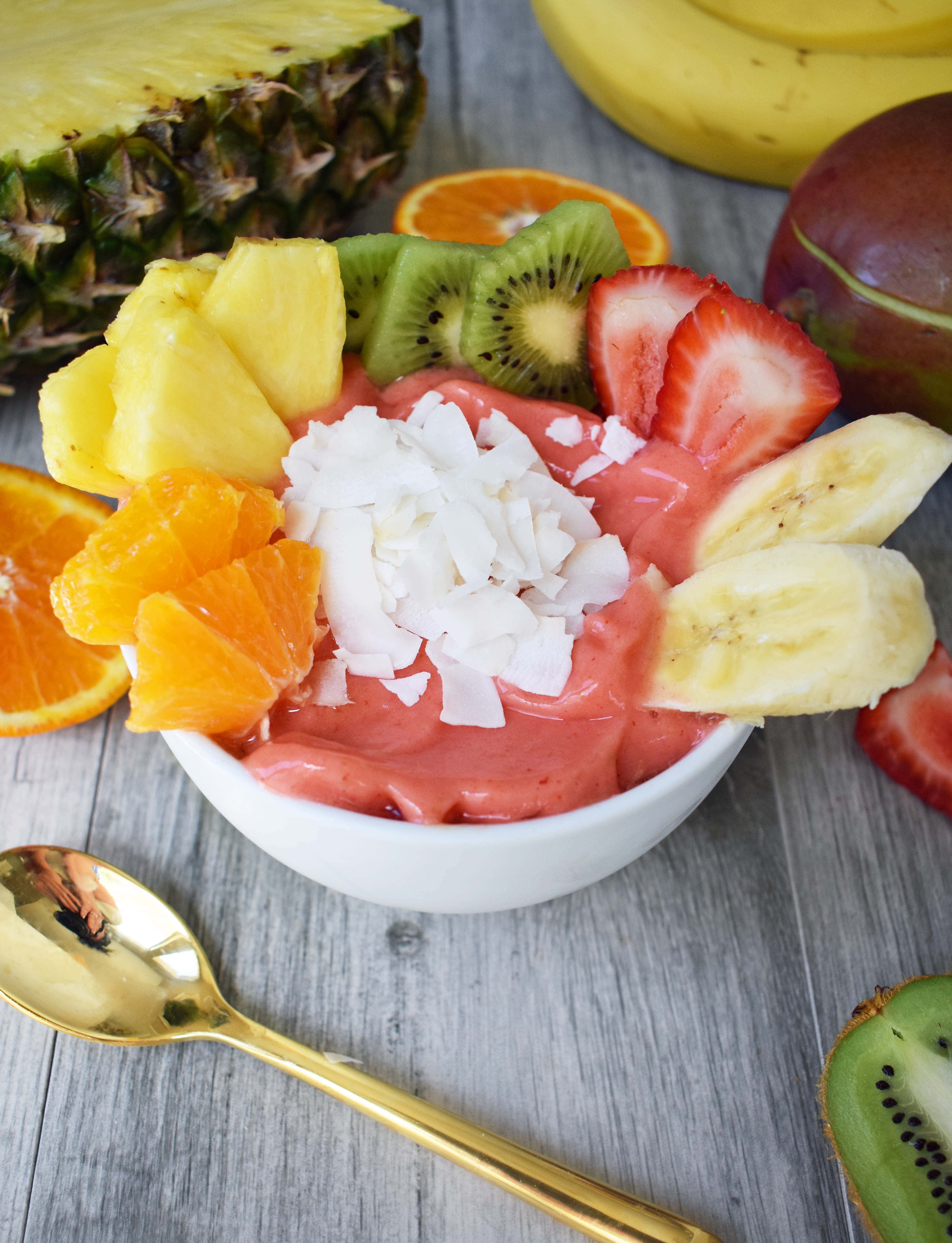 Kissed by Sunshine Smoothie Bowl made with frozen fruits, juice or coconut milk, and topped with fresh fruits, coconut shavings, and granola. A healthy and filling breakfast. www.modernhoney.com