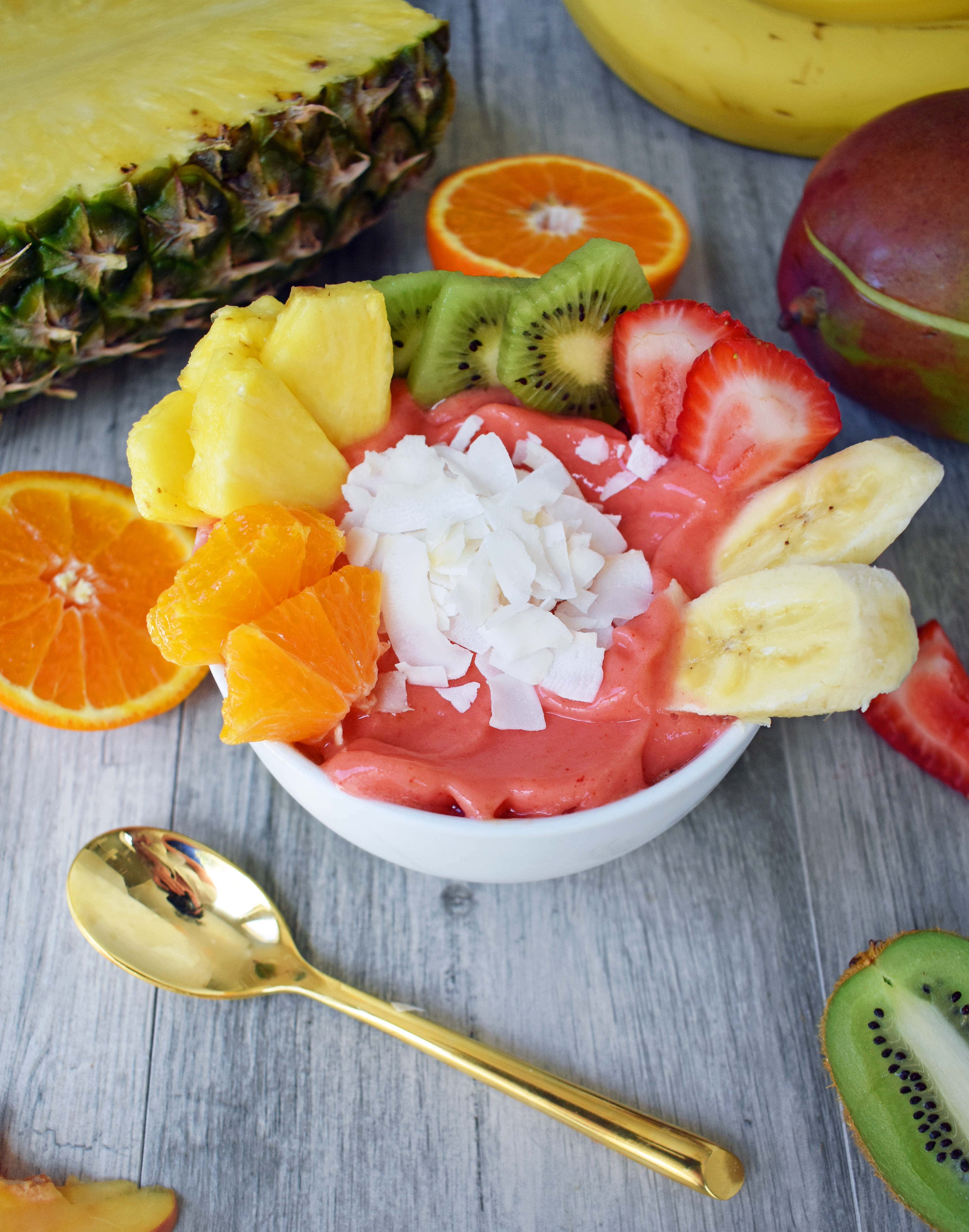 Kissed by Sunshine Smoothie Bowl made with frozen fruits, juice or coconut milk, and topped with fresh fruits, coconut shavings, and granola. A healthy and filling breakfast. www.modernhoney.com