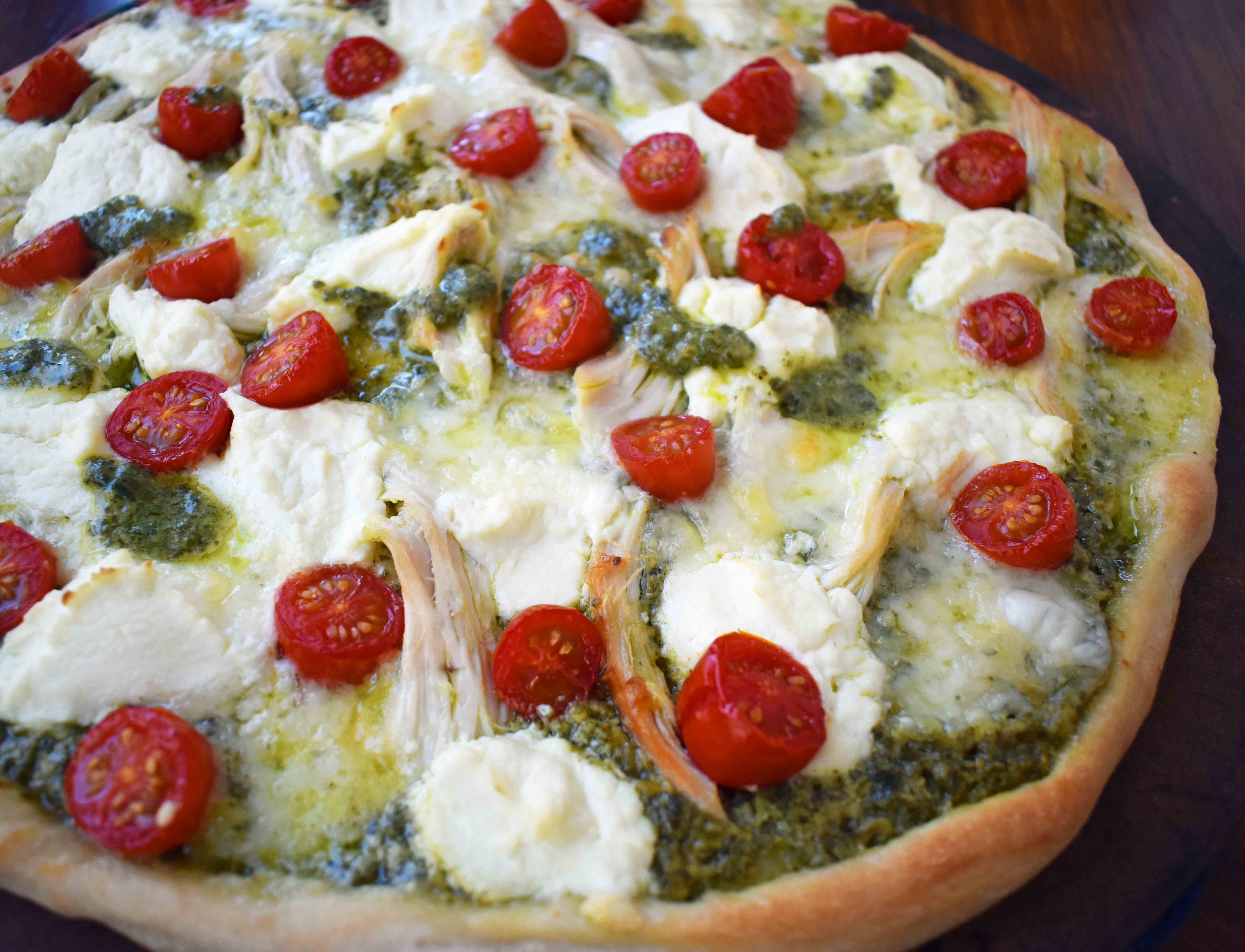 Chicken Pesto Pizza made with only 5 ingredients -- refrigerated pizza dough, pesto sauce, rotisserie chicken, ricotta cheese, and fresh mozzarella. May add grape tomatoes if so desired. An easy, flavorful homemade white pizza. www.modernhoney.com